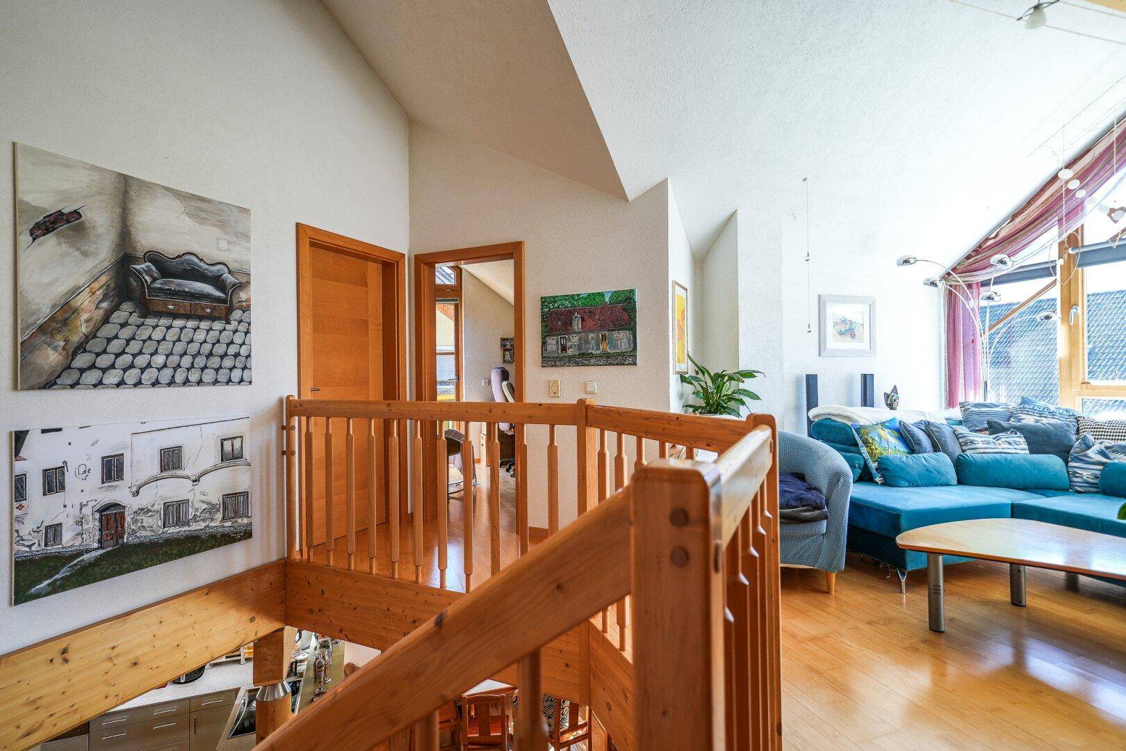 Offener Wohnbereich mit Holztreppe, Parkettboden und bequemer Couch.