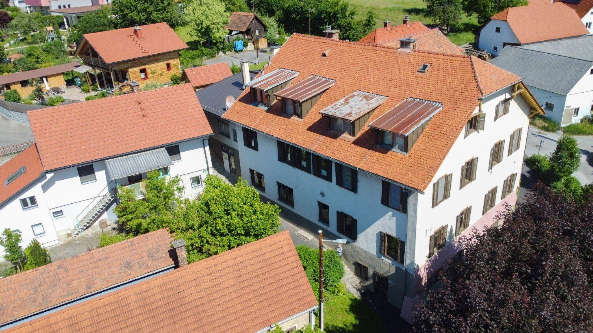 Dritte Luftaufnahme des Gebäudes mit Dachgauben und umgebenden Häusern.