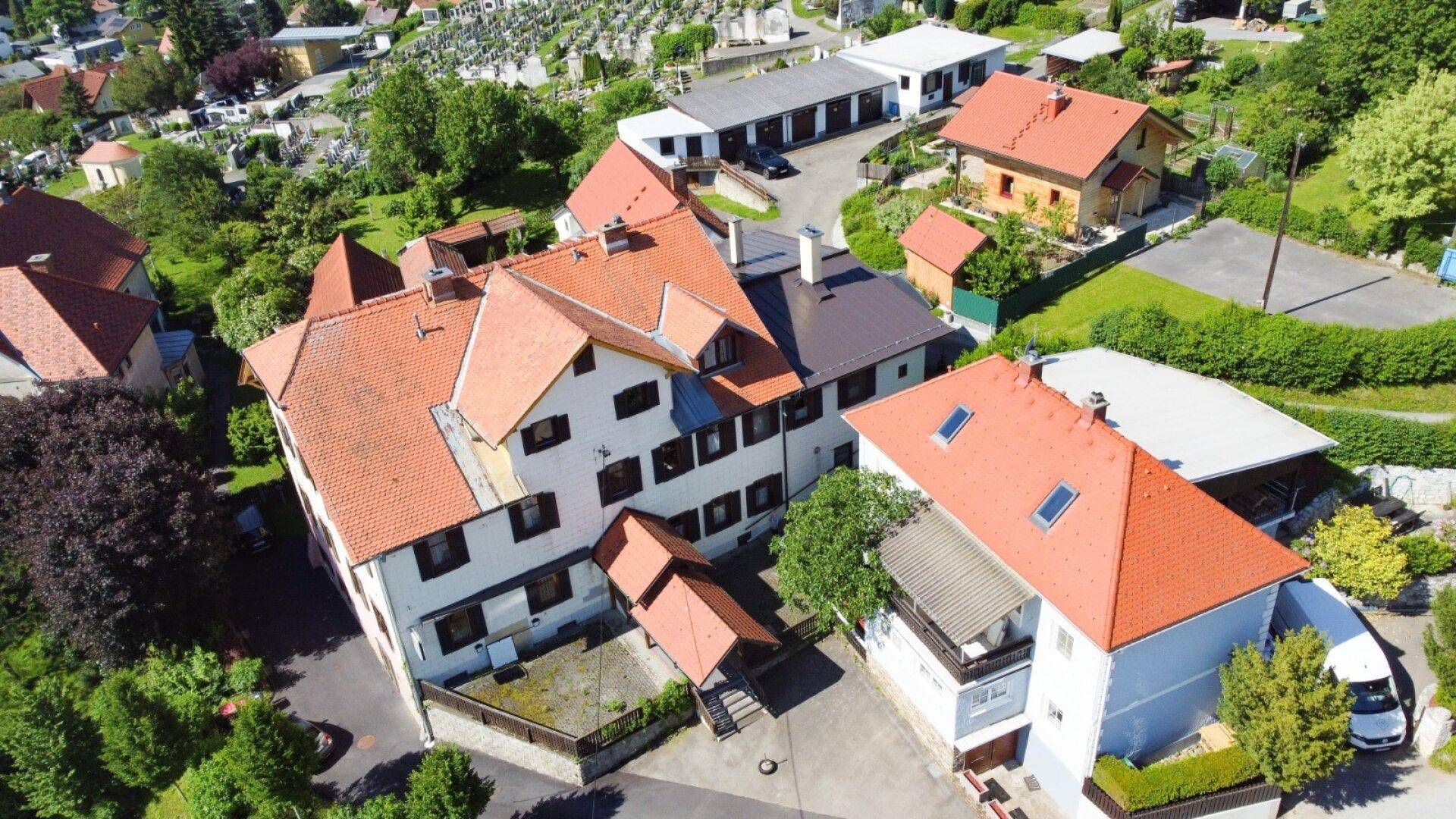 Weitläufige Luftaufnahme des Anwesens mit mehreren Gebäuden und viel Grün.