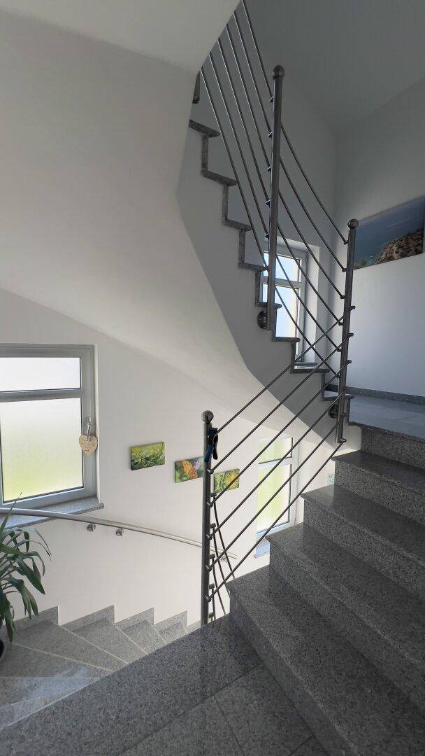 Geräumiger Treppenbereich mit großen Fenstern und viel Tageslicht.