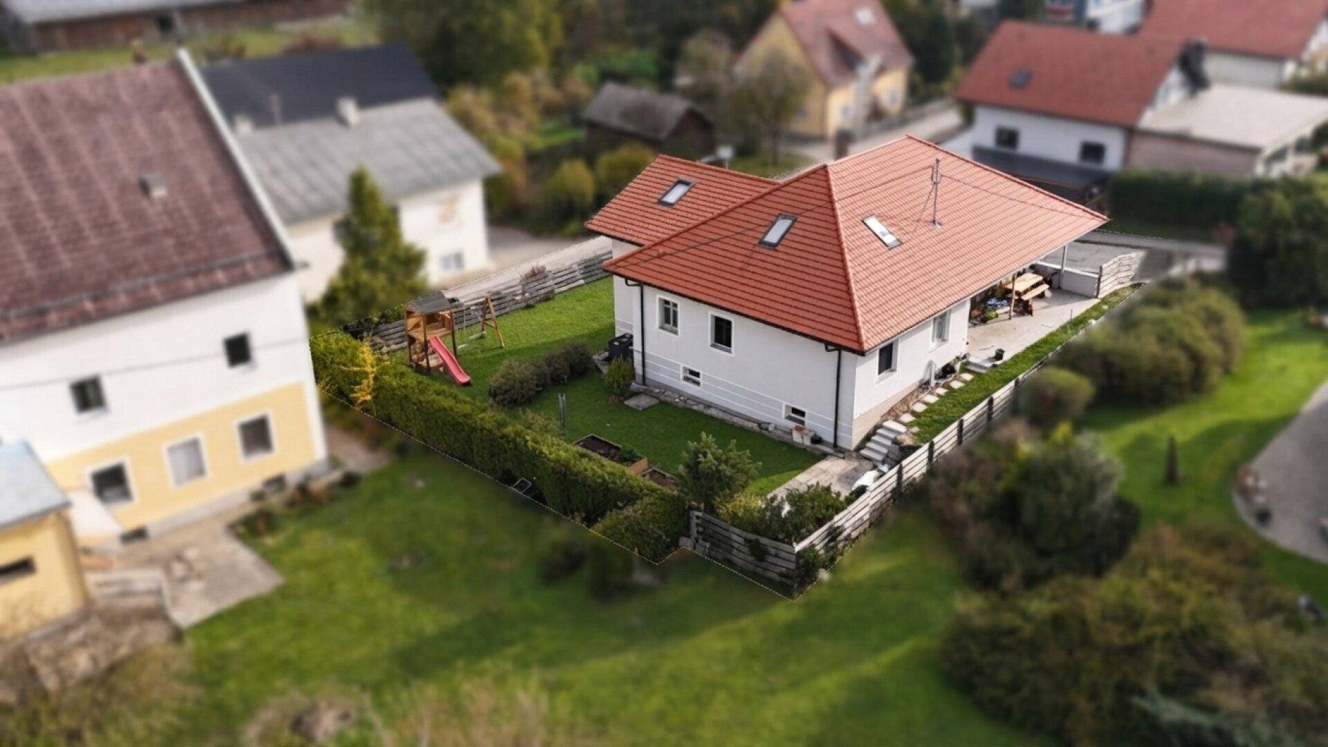 Rückansicht des Hauses mit großem Garten, Terrasse und Kinderspielplatz.