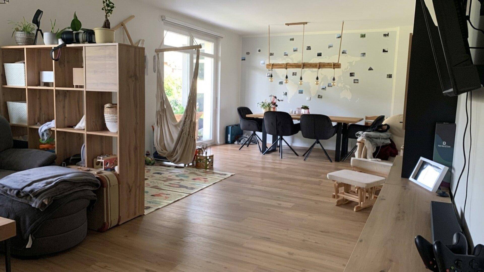 Offener Wohn- und Essbereich mit Holzboden, Hängematte und modernem Esstisch.