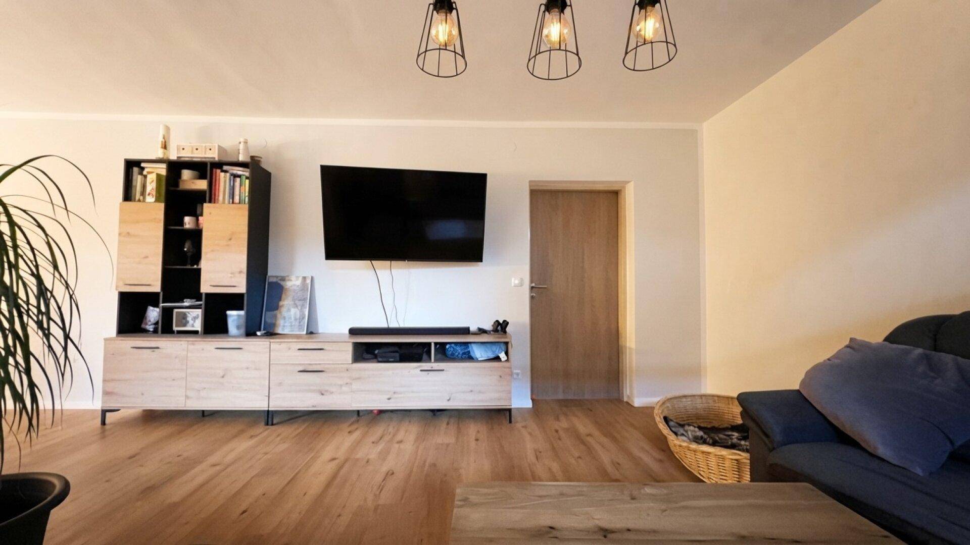 Gemütliches Wohnzimmer mit Holzboden, TV-Möbeln und indirekter Beleuchtung.