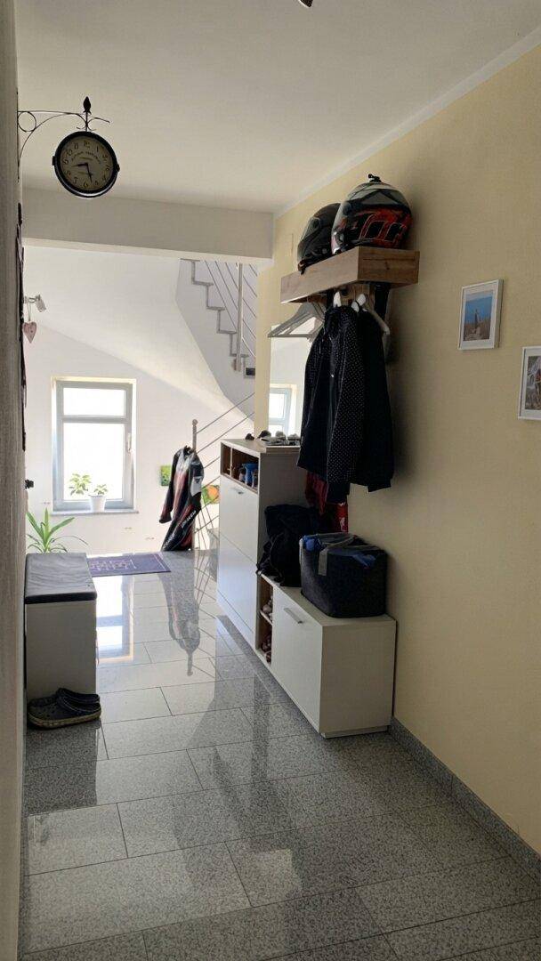 Eingangsbereich mit Fliesenboden, Garderobe und Blick auf den hellen Treppenaufgang.