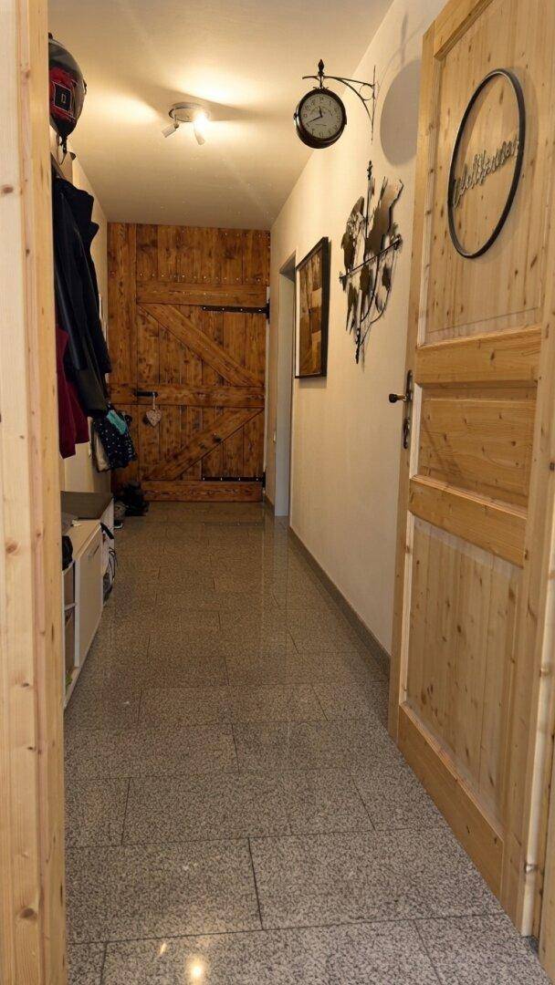 Flur mit hellen Fliesen, Holztüren und rustikalen Dekorationselementen.