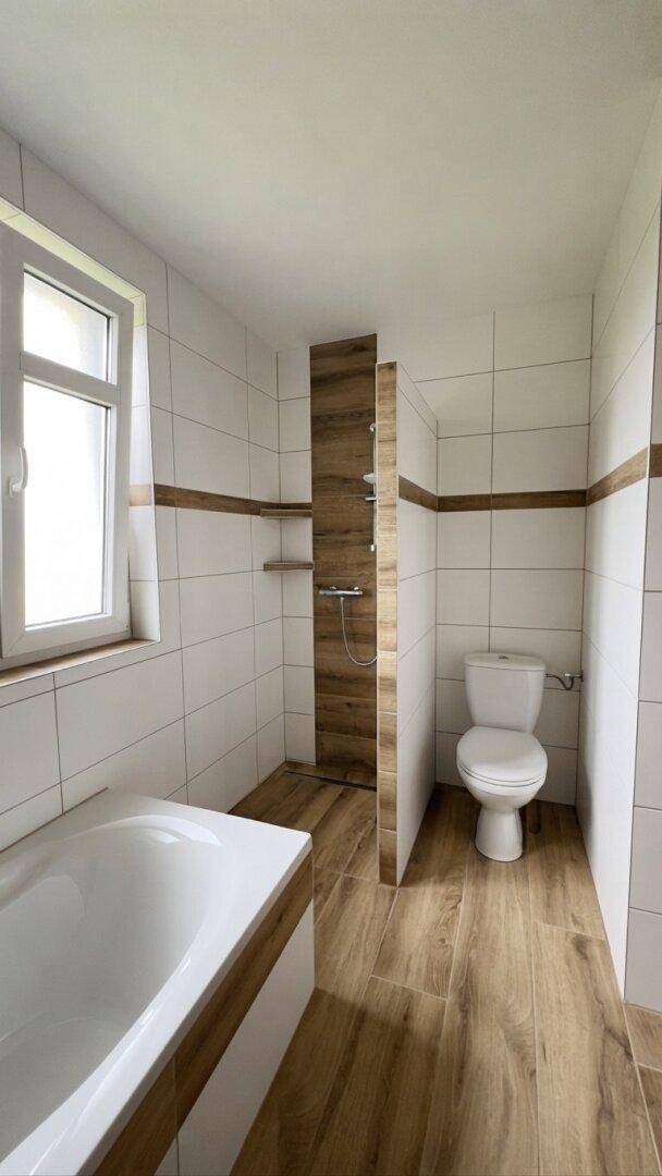 Modernes Badezimmer mit Badewanne, Dusche und WC, hell gefliest.