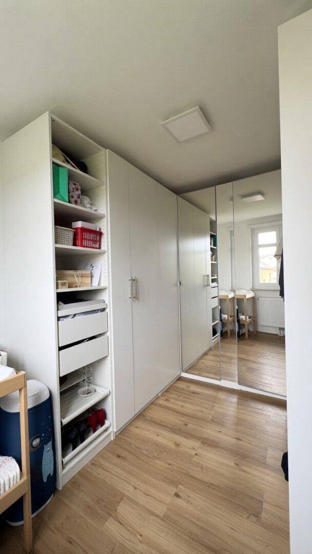 Schlafzimmer mit Holzboden, weißen Einbauschränken und Spiegelfronten.