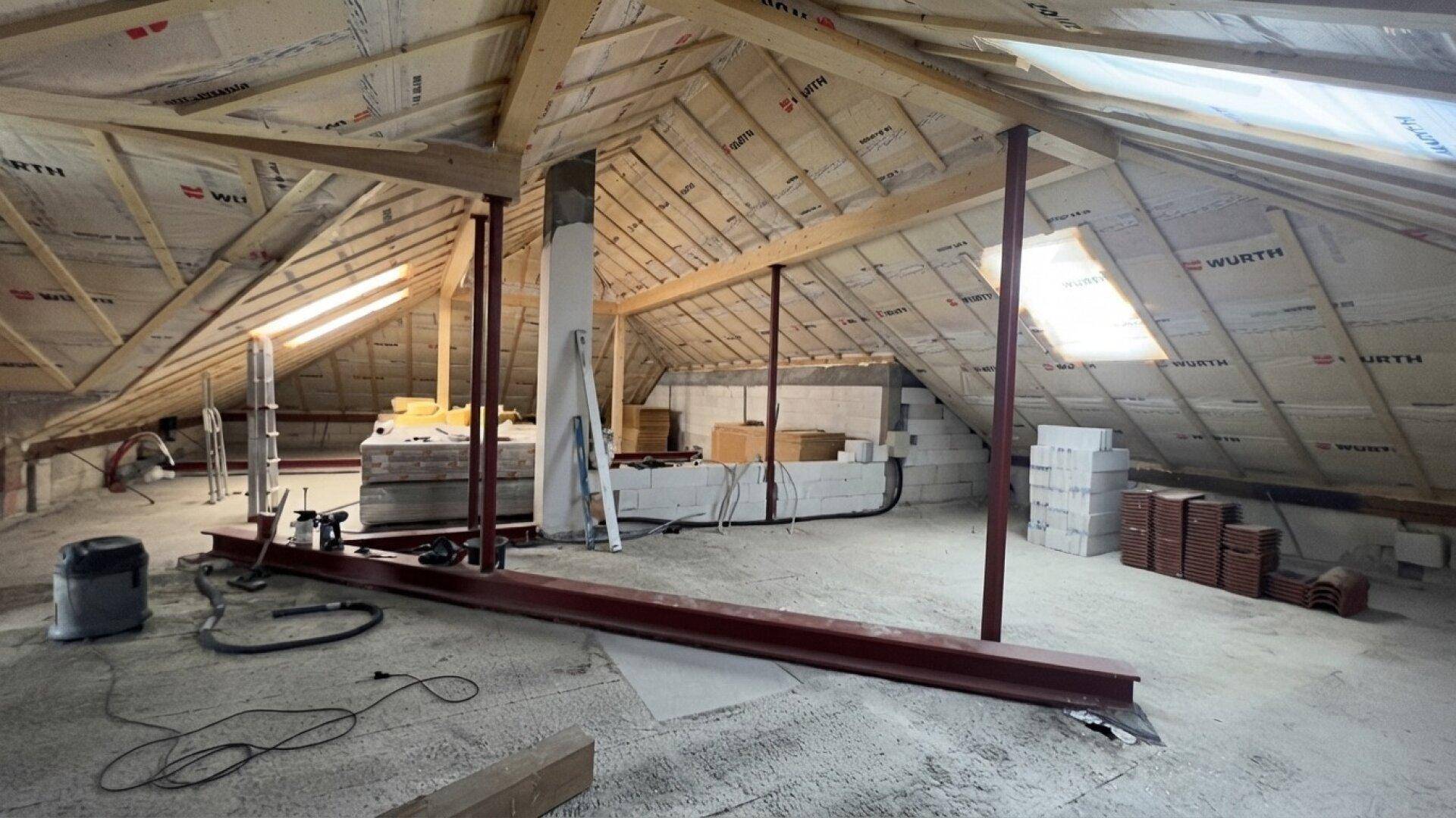 Unausgebauter Dachboden mit sichtbarer Holzkonstruktion und Dachfenstern.