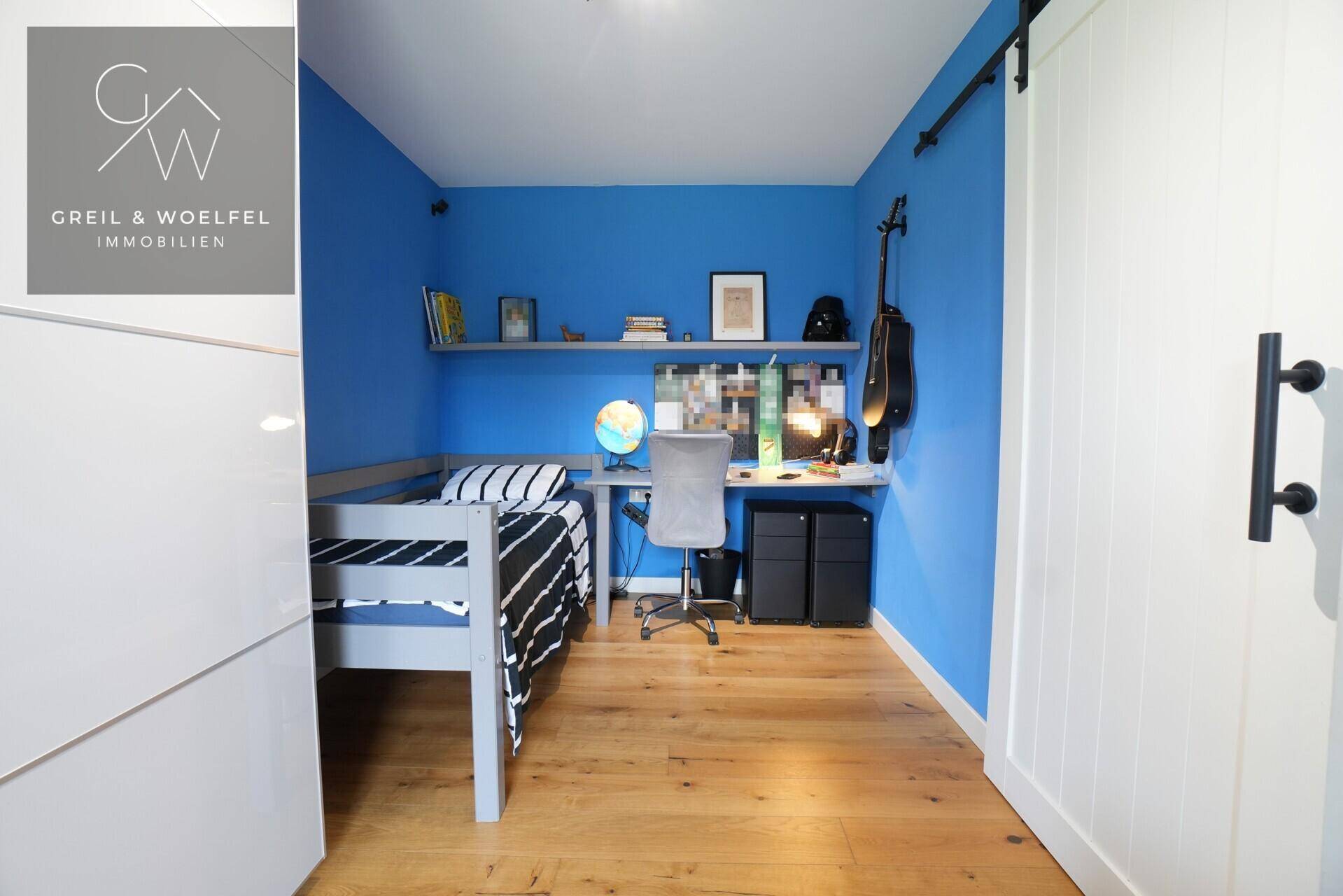 Lebhaftes Kinderzimmer mit blauen Wänden, Holzboden und einem Schreibtischbereich.