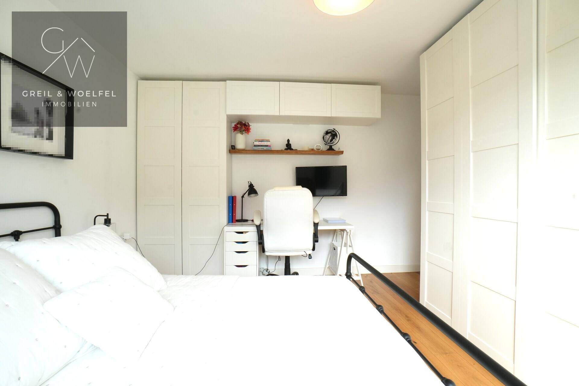 Funktionales Schlafzimmer mit integrierten Kleiderschränken und einem gut organisierten Arbeitsplatz.