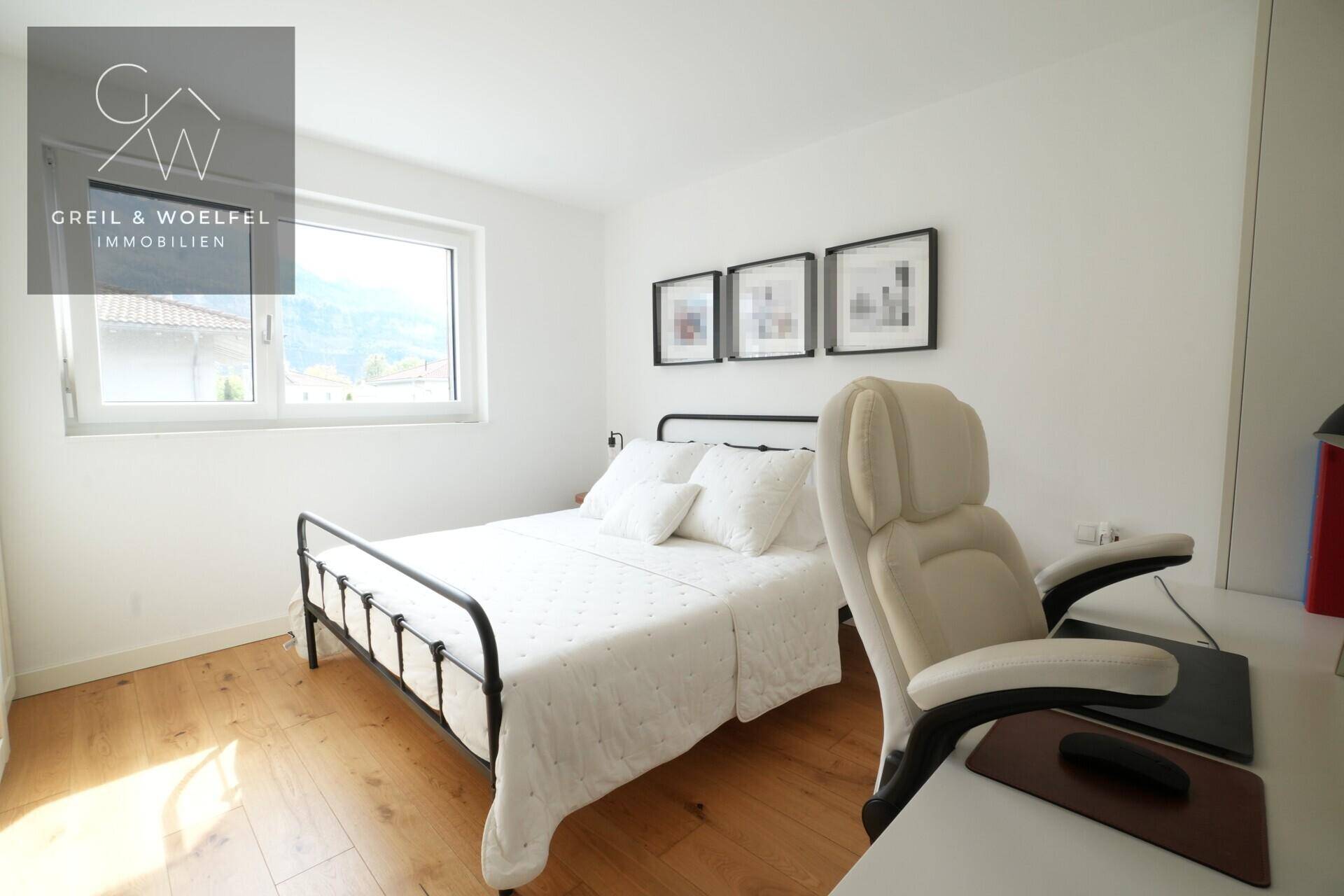 Gemütliches Schlafzimmer mit Holzboden, Fenster und einem praktischen Arbeitsbereich.