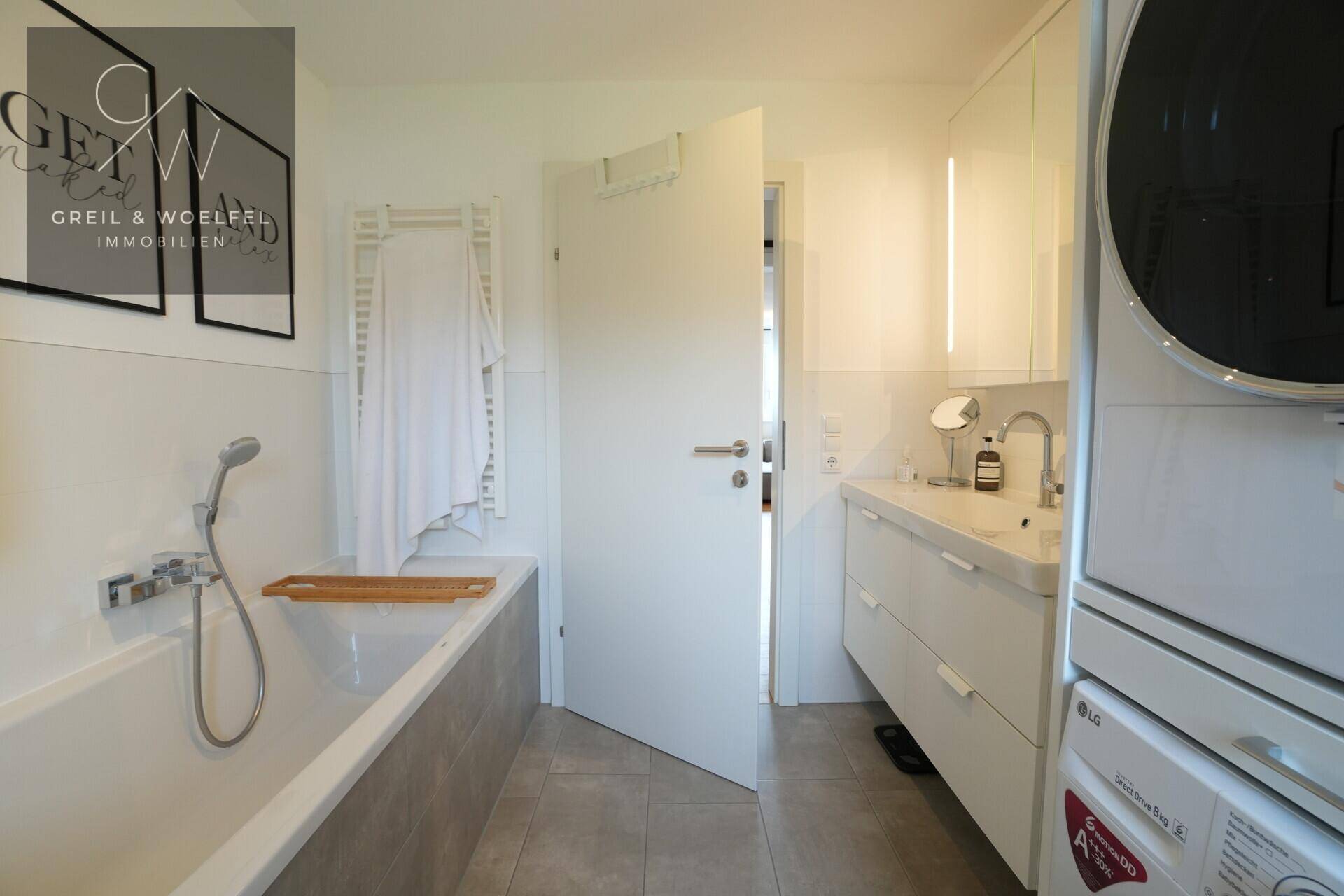 Modernes Badezimmer mit Badewanne, Waschbecken und integrierter Waschmaschine.