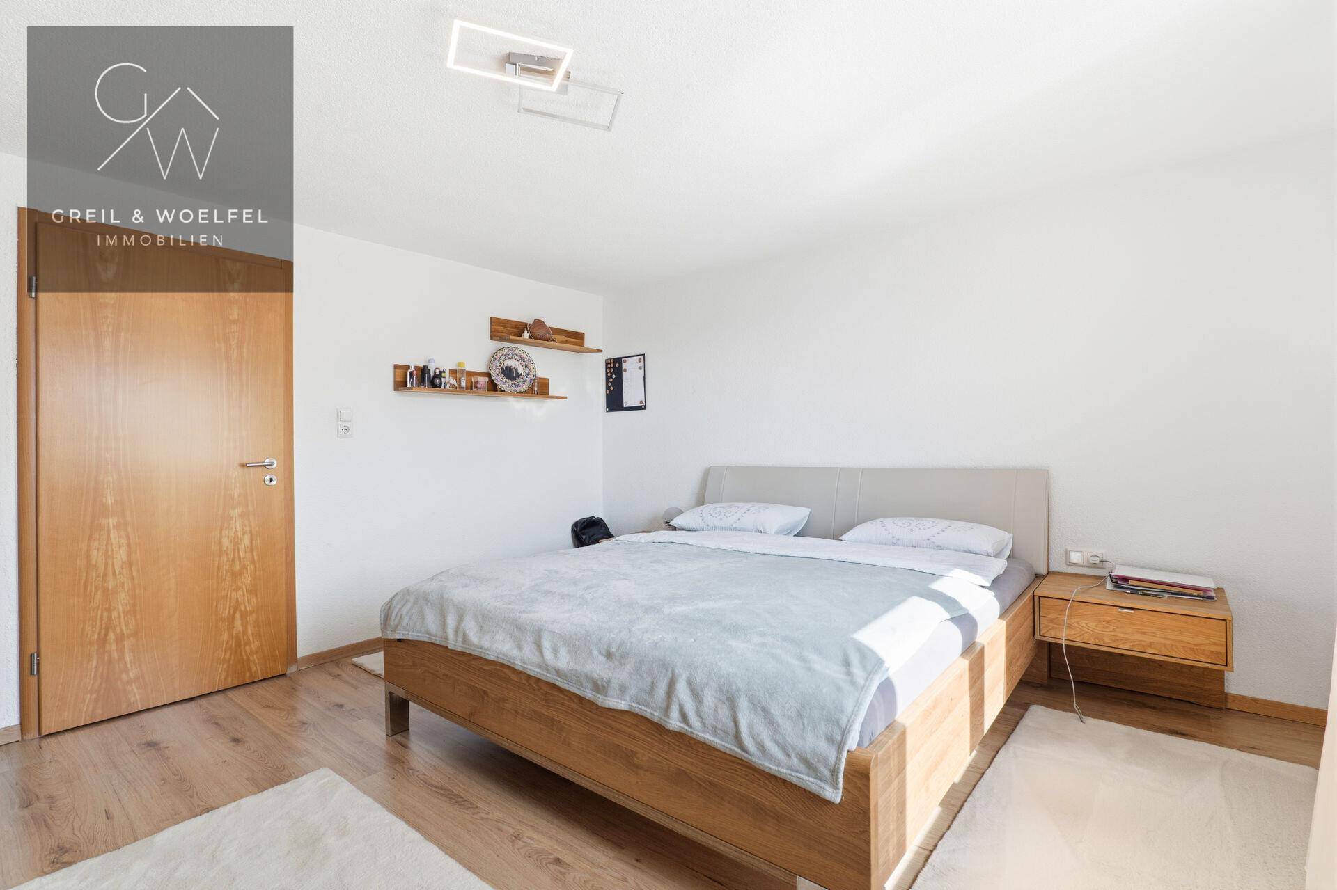 Schlafzimmer mit Holzbett, Nachttisch und Holztür, das eine ruhige Atmosphäre bietet.