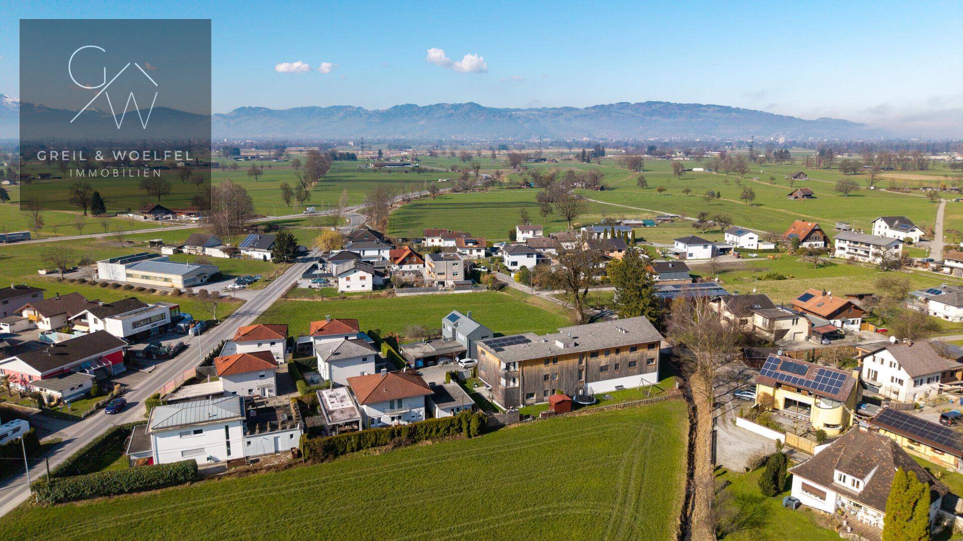 Weitläufige Luftaufnahme der ländlichen Umgebung mit Wohnsiedlung und Bergpanorama.