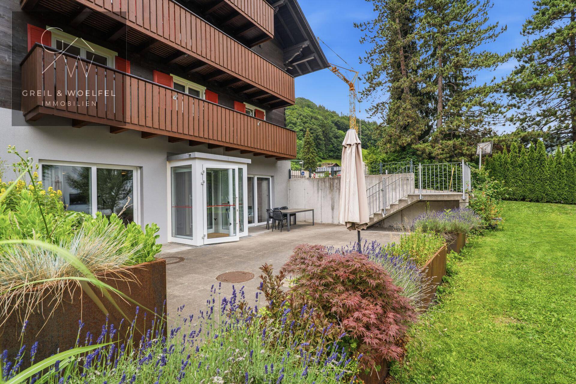 Gepflegter Gartenbereich mit Terrasse, Sitzgelegenheiten und blühenden Pflanzen.