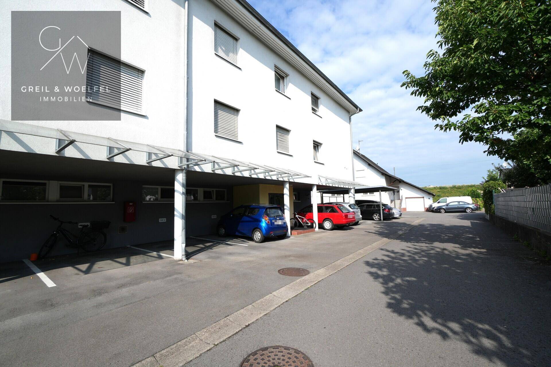 Überdachte Parkplätze unter einem Carport neben dem Mehrfamilienhaus.