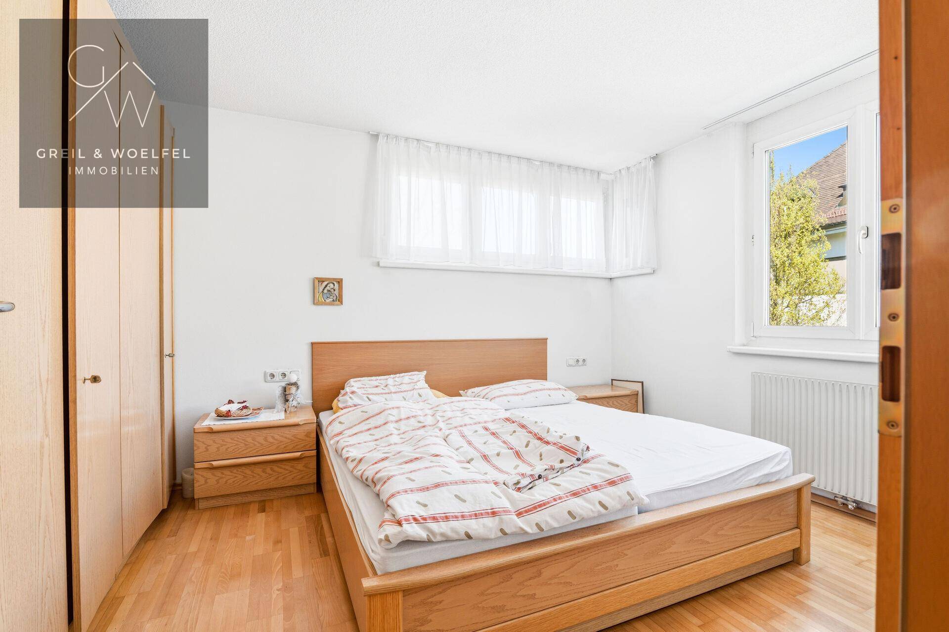 Gemütliches Schlafzimmer mit Doppelbett, Holzmöbeln und Parkettboden.