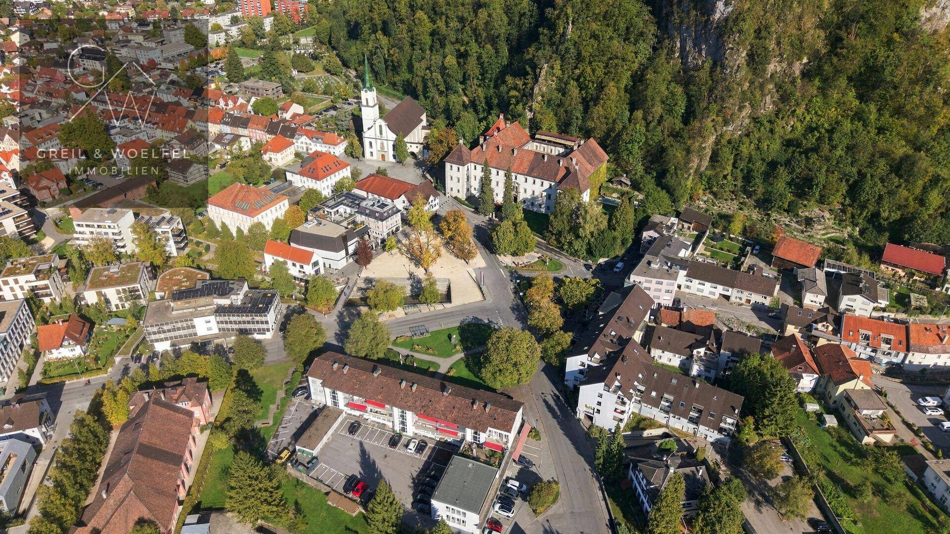 Panoramische Luftaufnahme einer Stadt mit historischen Gebäuden und grünen Hügeln.