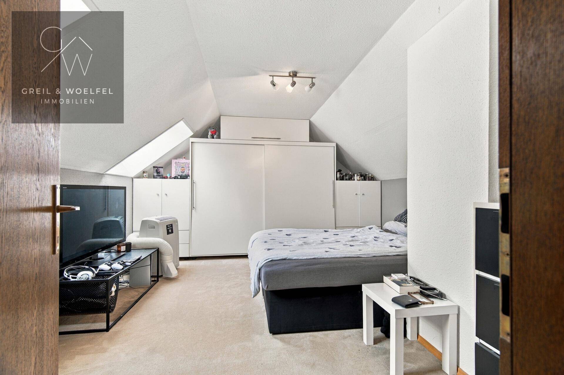 Schlafzimmer im Dachgeschoss mit Teppichboden, Einbauschränken und Dachschrägen.