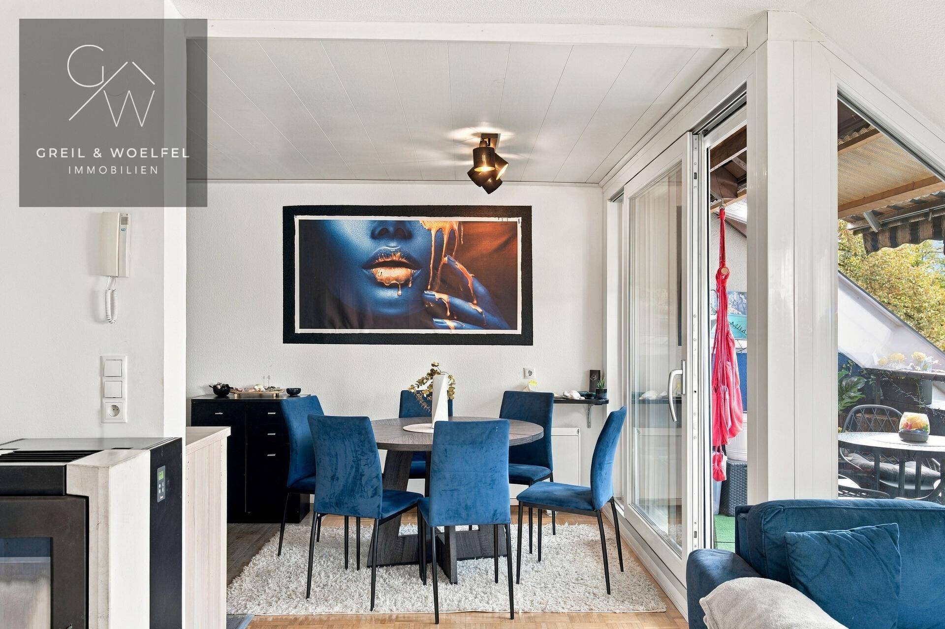 Essbereich mit modernem Esstisch und blauen Stühlen, angrenzend an einen Balkon.