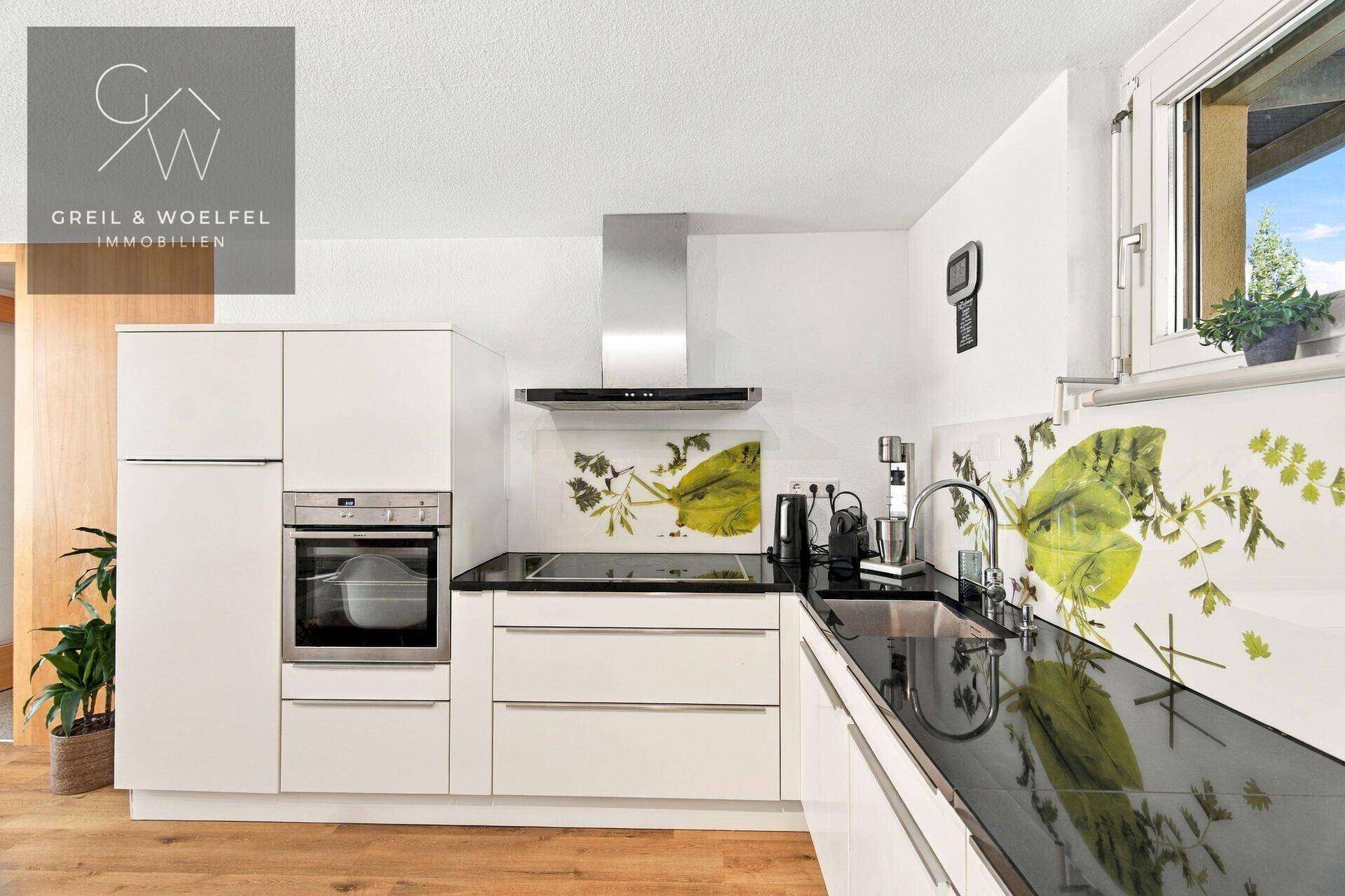 Moderne Einbauküche mit dunkler Arbeitsplatte, Spüle und Fenster für Tageslicht.