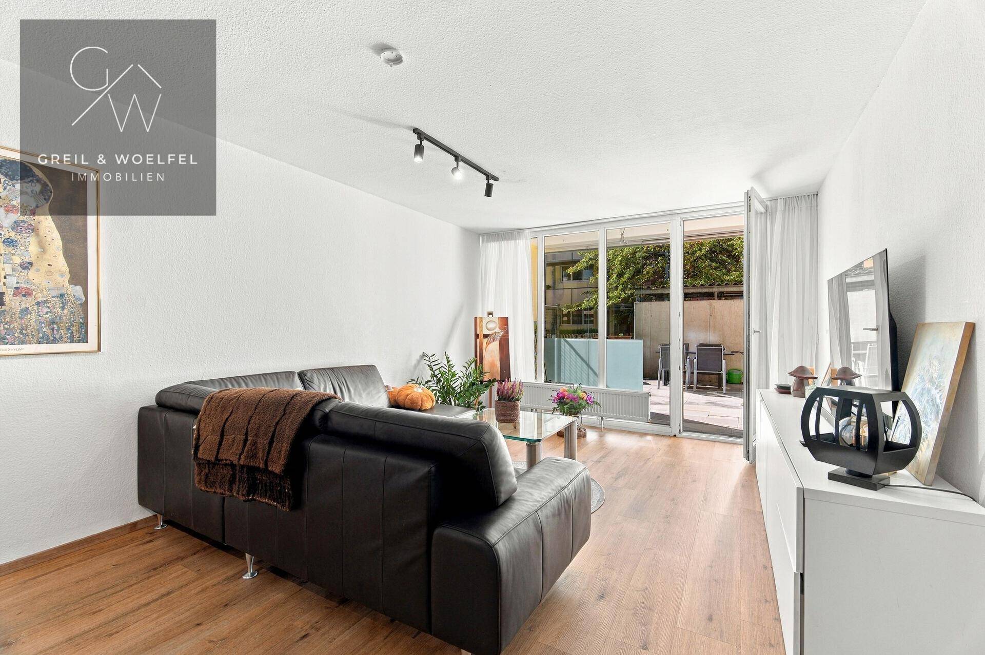 Gemütliches Wohnzimmer mit Sofa, Fernseher und direktem Zugang zur Terrasse.
