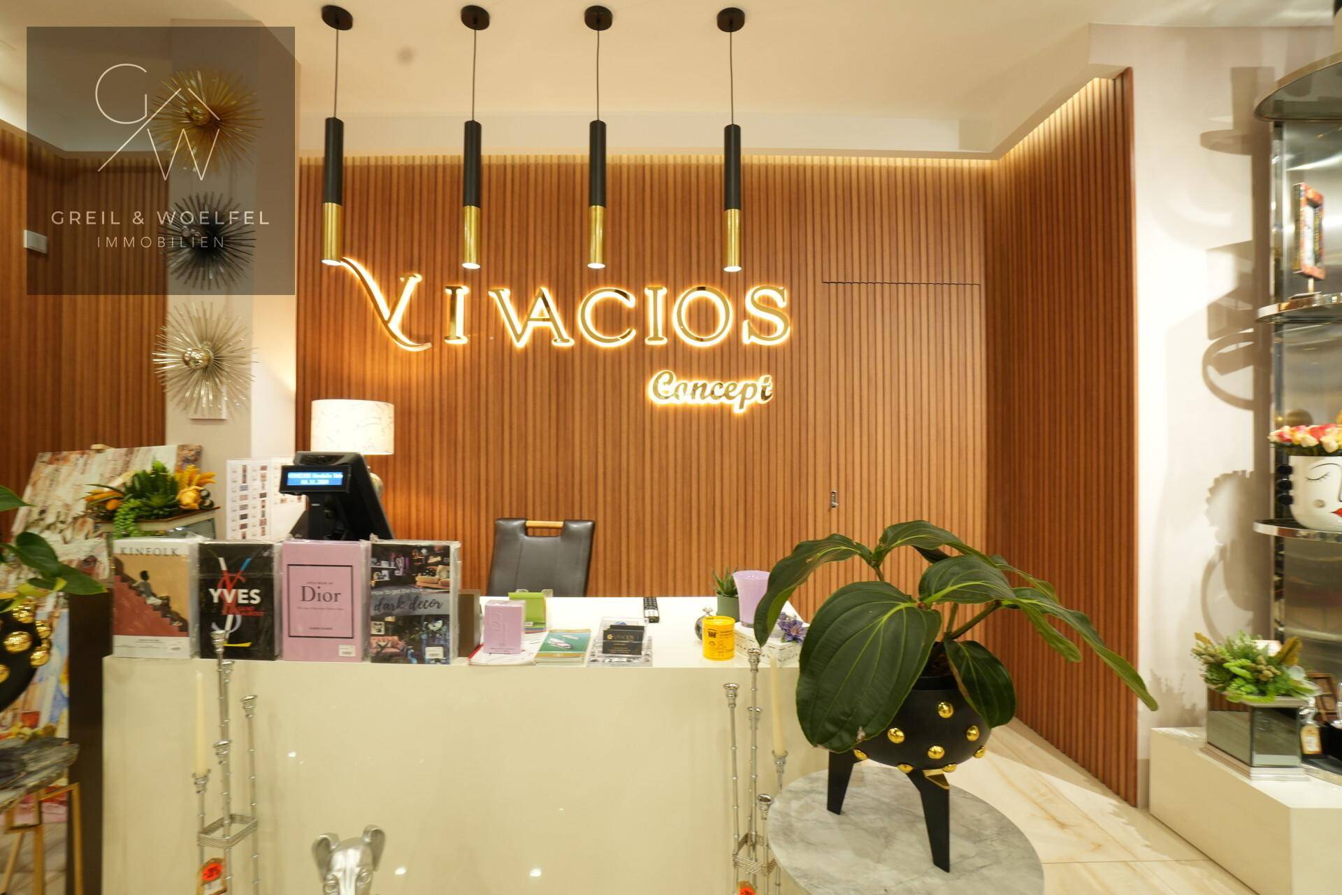 Empfangsbereich mit Holzlamellenwand, beleuchtetem Logo und moderner Theke.