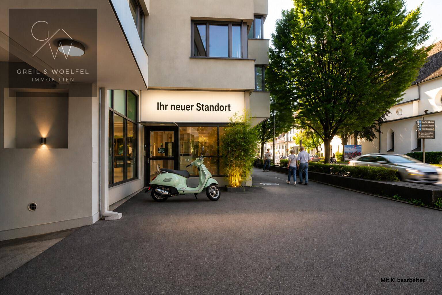 Eingangsbereich eines modernen Geschäftsgebäudes mit Schaufenstern und Außenbeleuchtung.