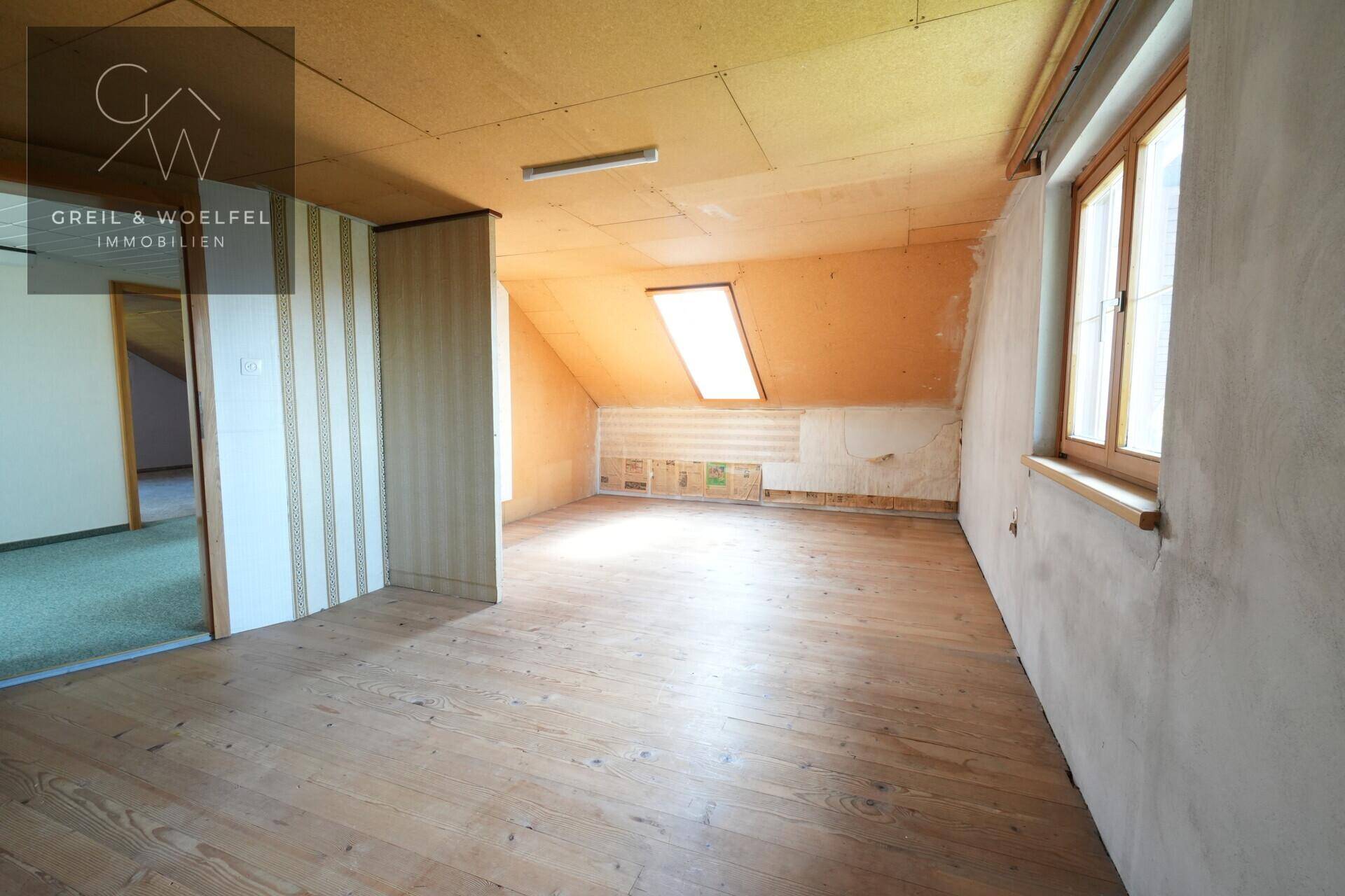 Geräumiger Dachboden mit Holzdielenboden, Dachfenster und schrägen Wänden, vielseitig nutzbar.