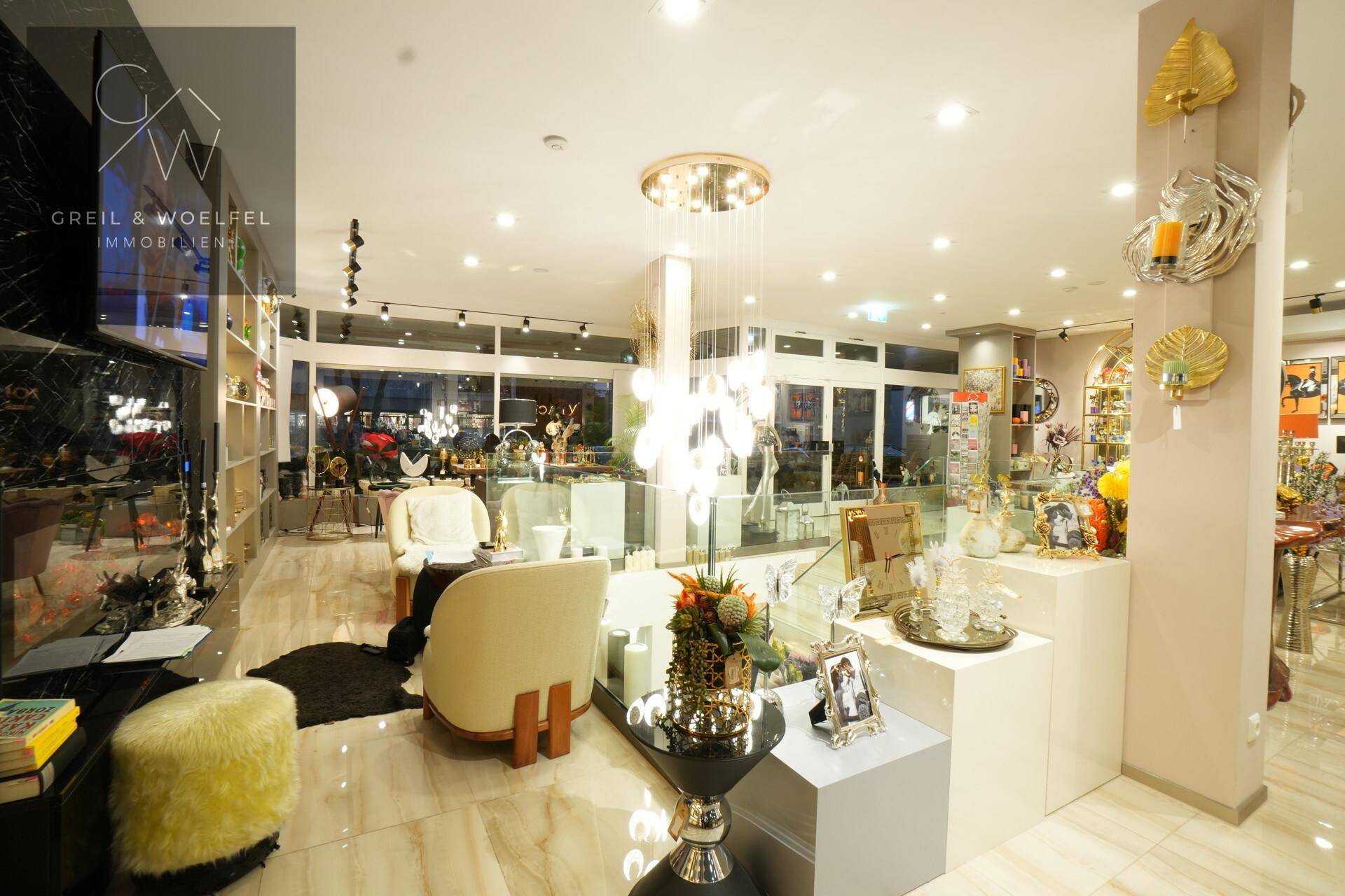 Heller Verkaufsraum mit stilvollen Sitzgelegenheiten, dekorativer Beleuchtung und großen Fensterfronten.