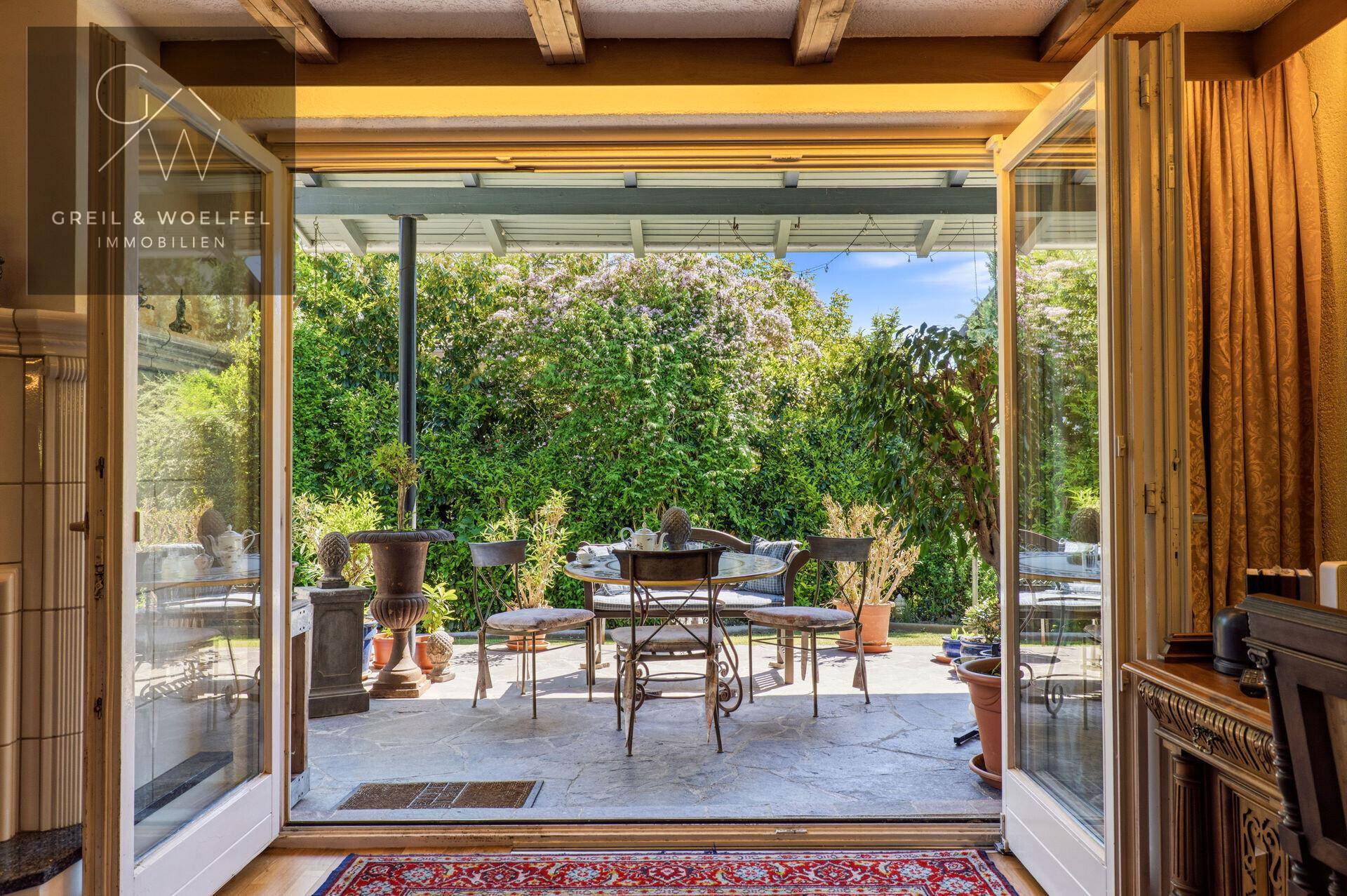 Heller Wohnbereich mit Zugang zu einer grünen, überdachten Terrasse, ideal für den Übergang nach draußen.