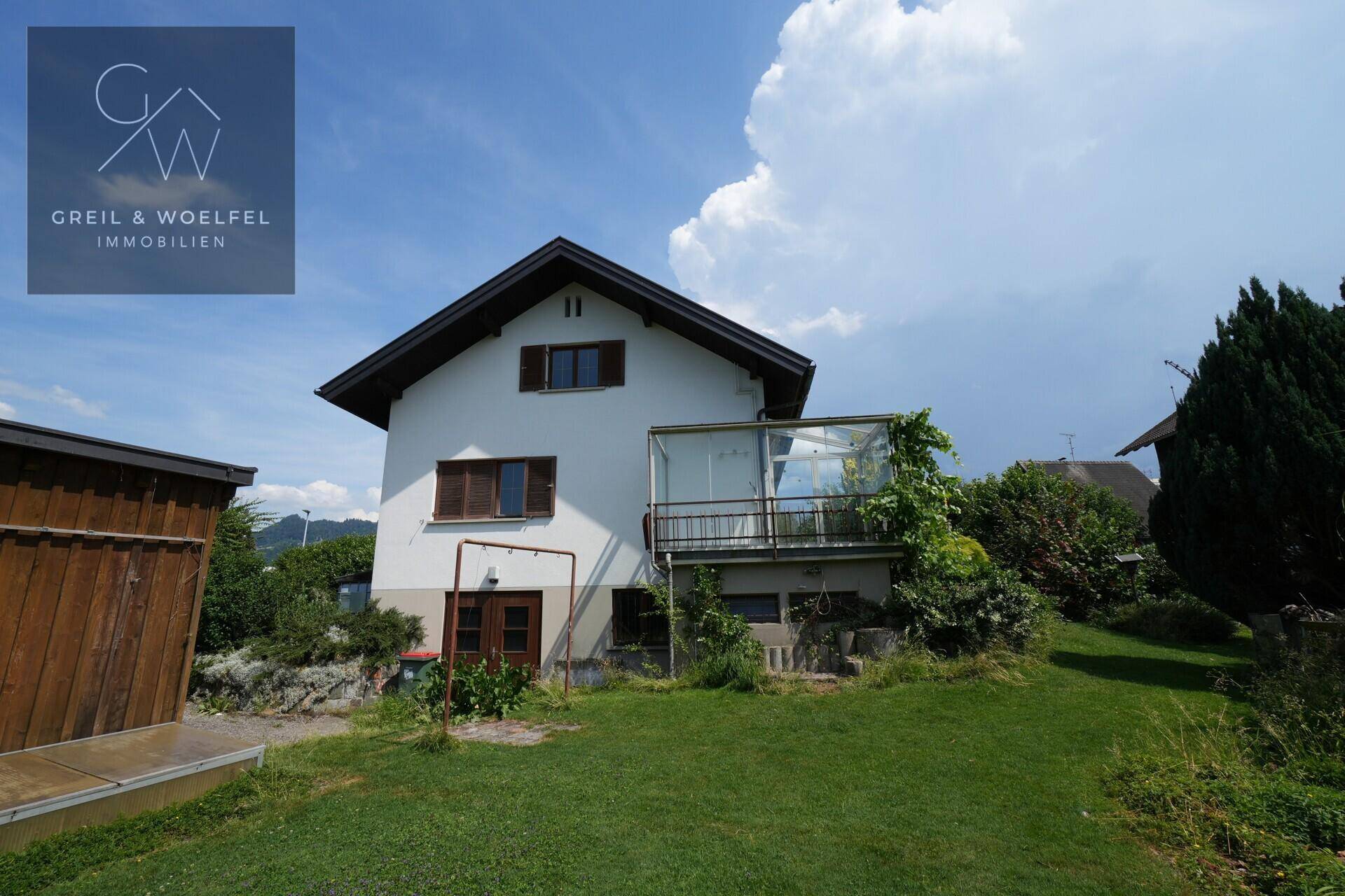 Rückansicht des Hauses mit Wintergarten, Balkon und großem Gartenbereich.