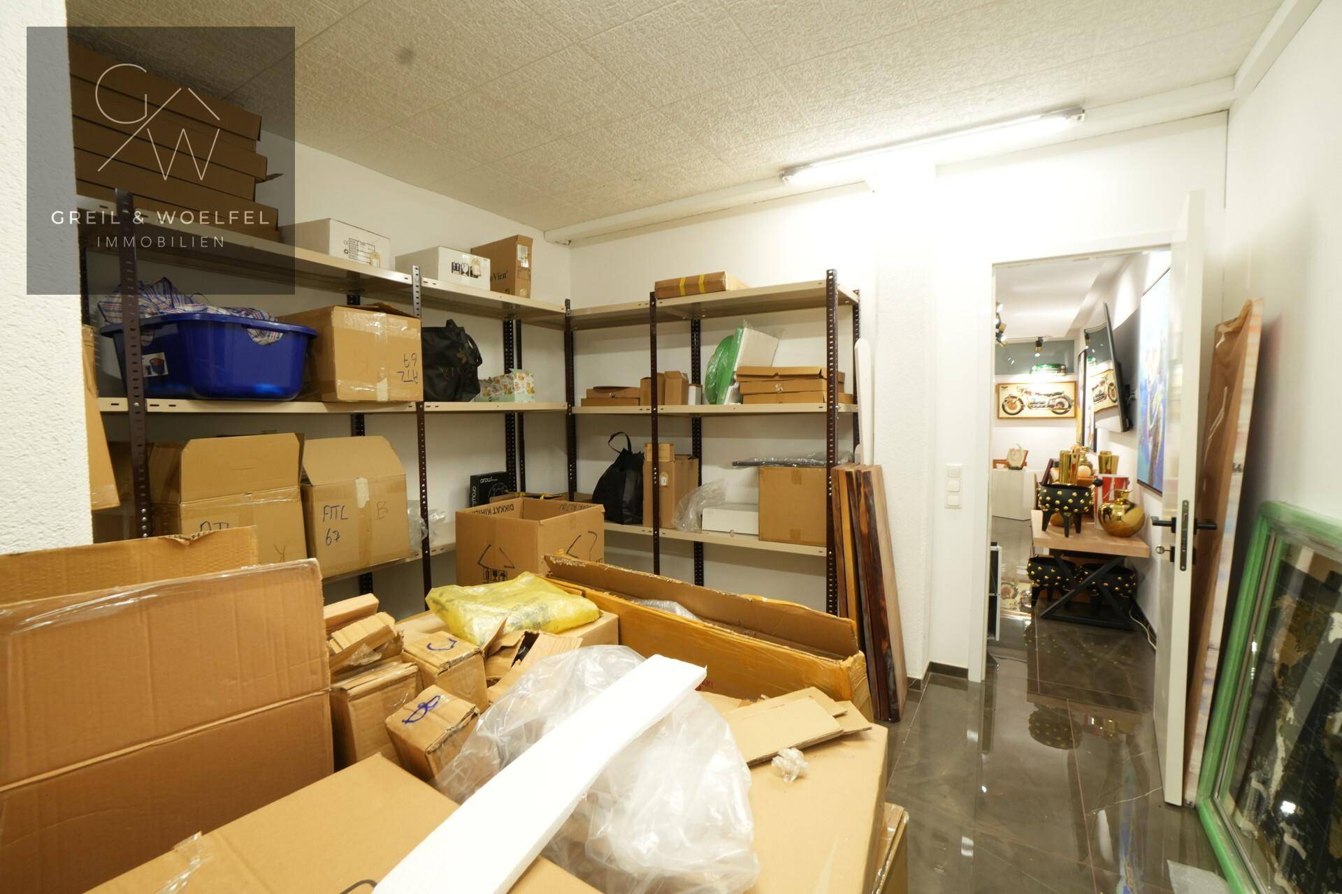 Lagerraum mit Regalen voller Kartons und verschiedenen Gegenständen, gut organisiert.