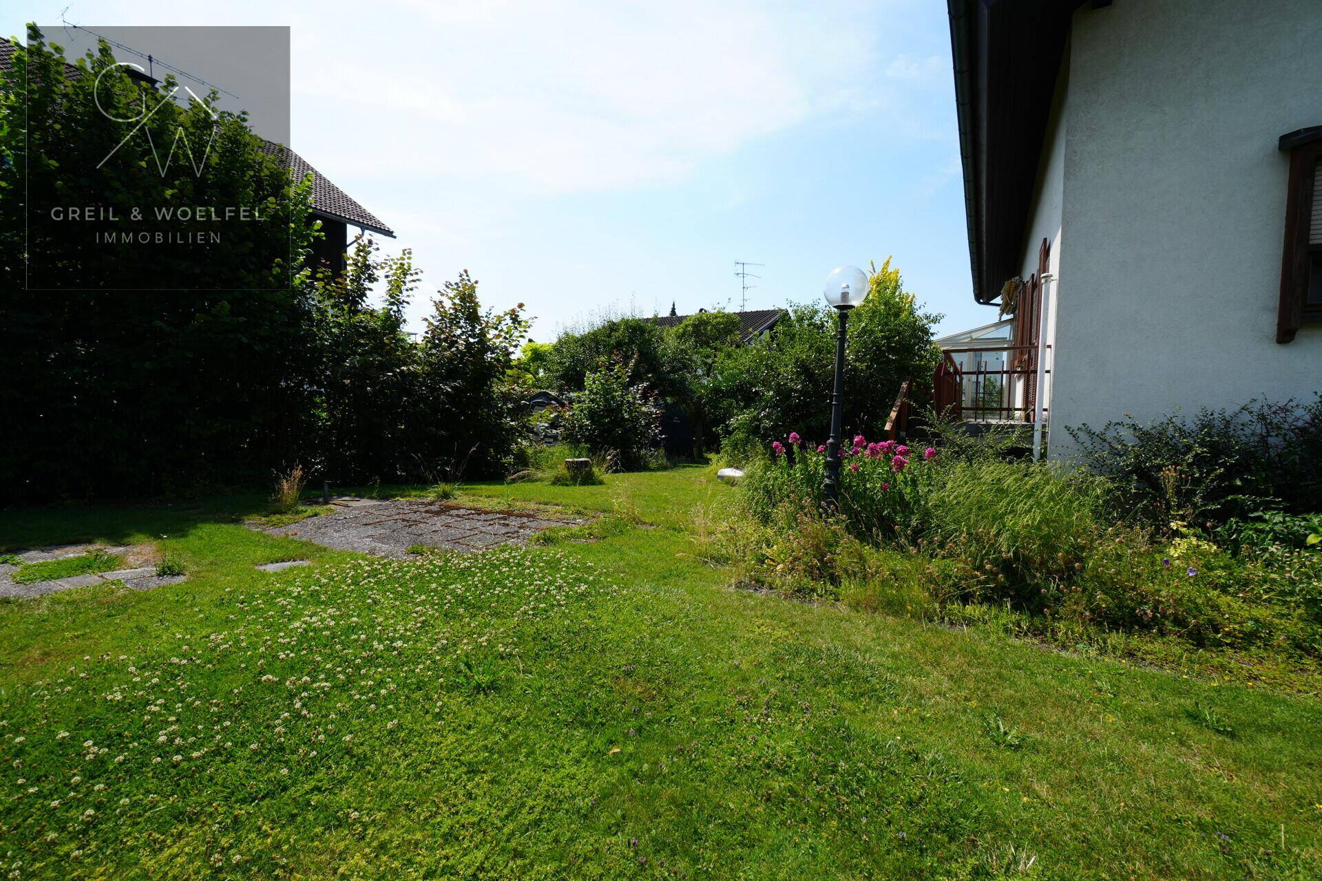 Gepflegter Gartenbereich mit Rasenfläche, Blumenbeeten und Sträuchern, ideal zum Entspannen.