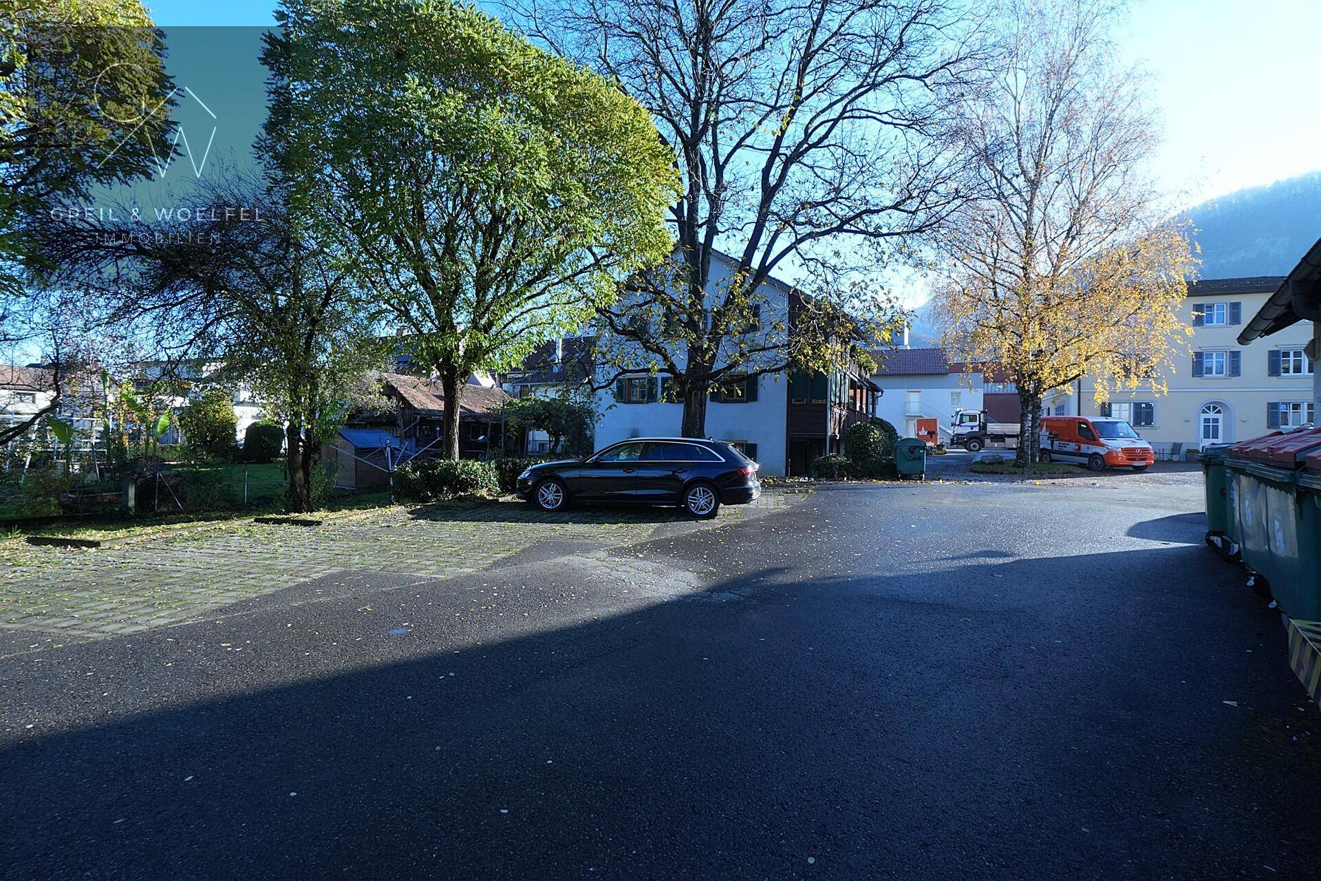 Außenansicht des Gebäudes mit Parkplätzen und Bäumen an einem sonnigen Tag.