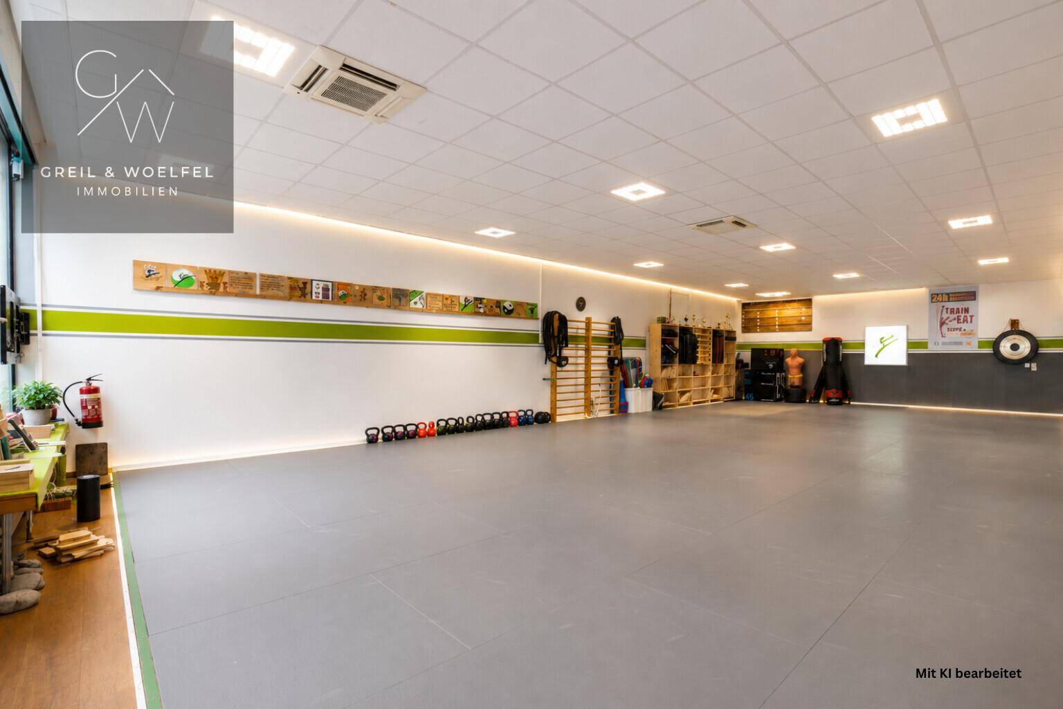 Geräumiger Fitnessraum mit Sportgeräten, Spiegelfront und moderner Beleuchtung.