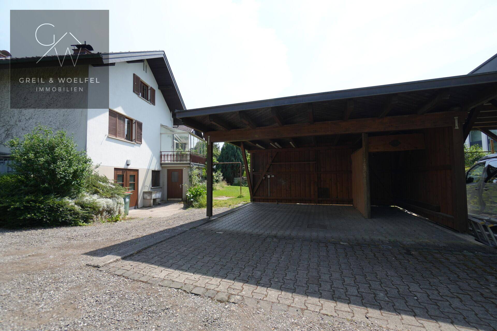 Haus mit großem Carport und gepflasterter Einfahrt, bietet geschützten Parkplatz.
