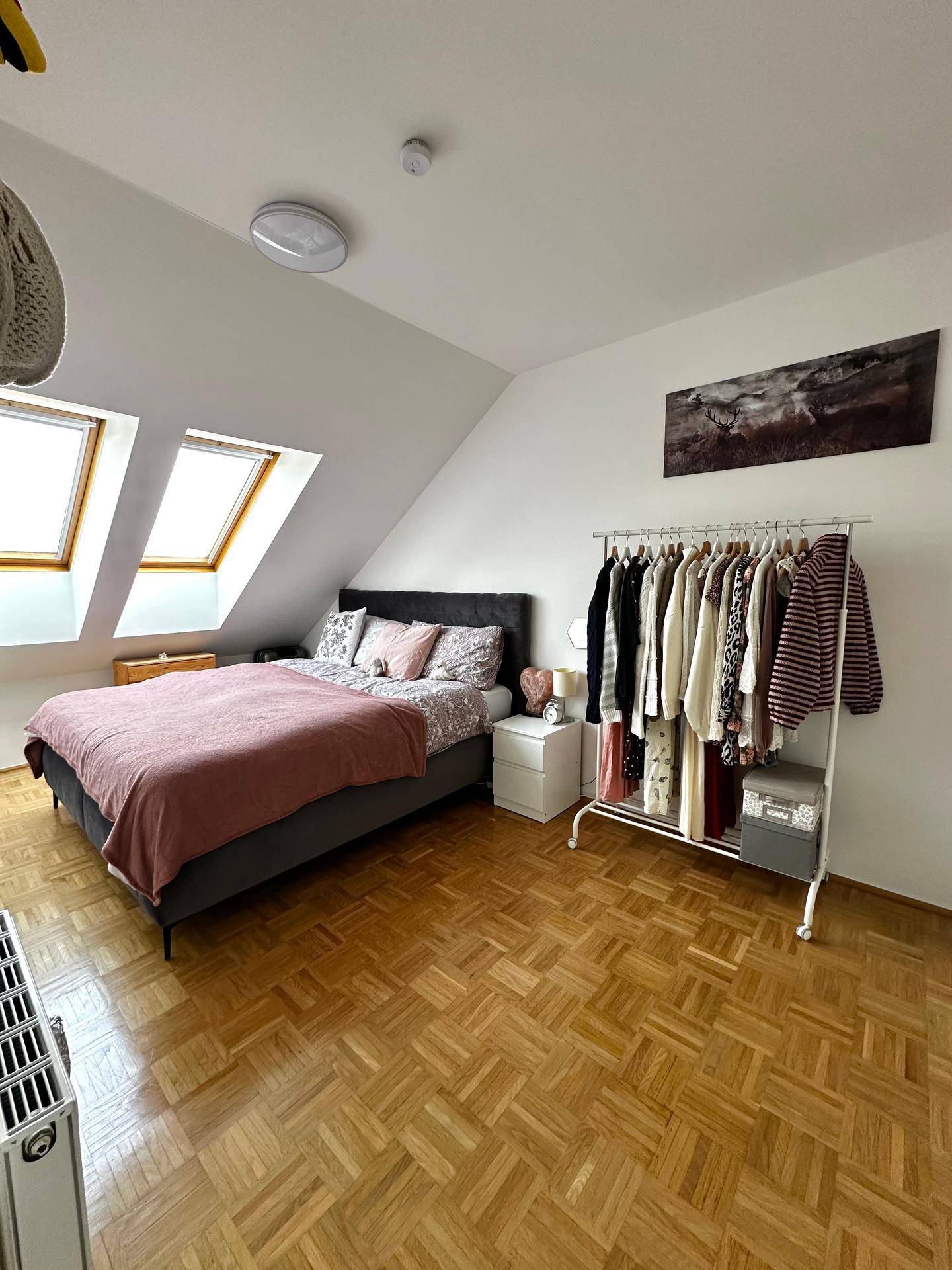 Gemütliches Schlafzimmer im Dachgeschoss mit Dachfenstern, Holzboden und schräger Decke.
