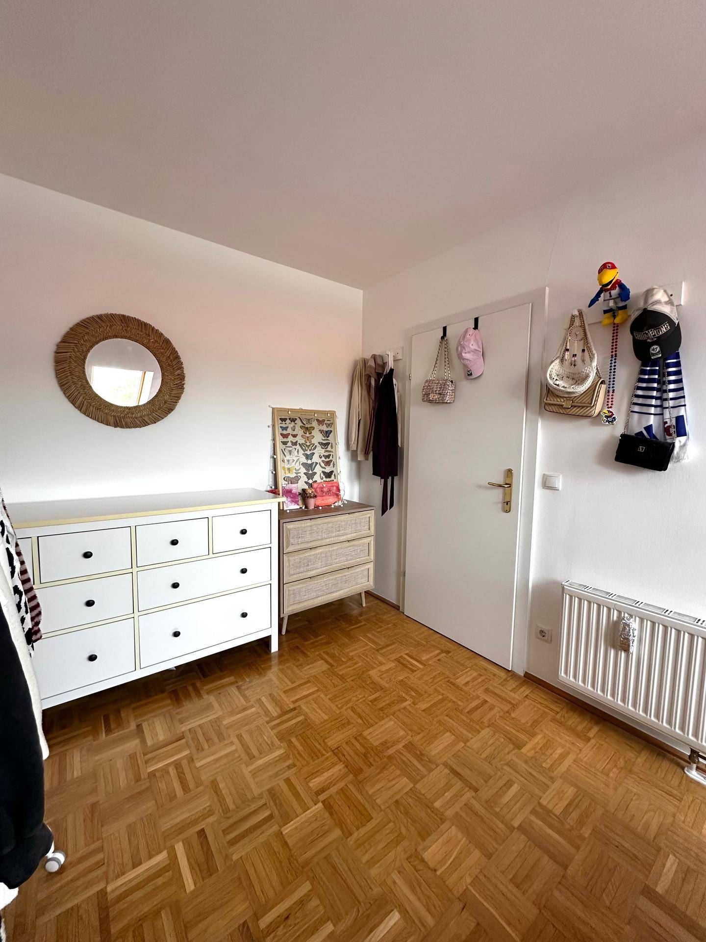 Detailansicht des Schlafzimmers mit Kommoden, Spiegel und Accessoires an der Wand.