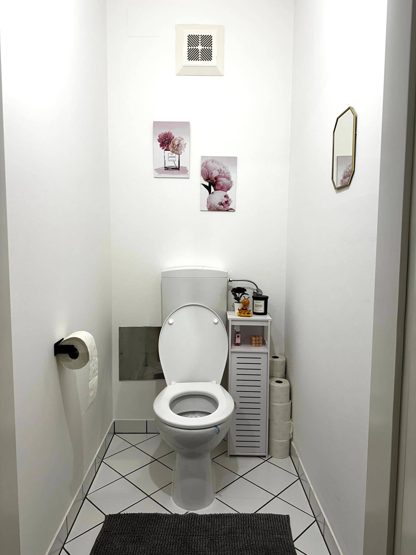 Kleines Gäste-WC mit weißen Fliesen, Toilette und minimalistischer Dekoration an der Wand.