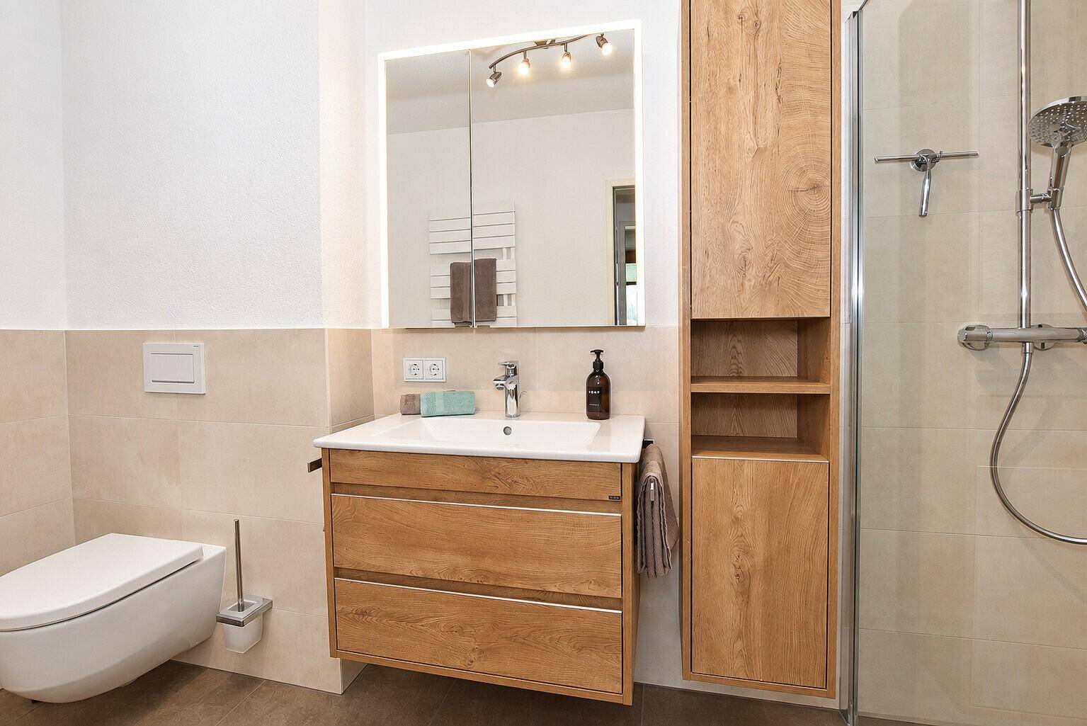 Modernes Badezimmer mit Holzwaschtisch, begehbarer Dusche und Wand-WC.