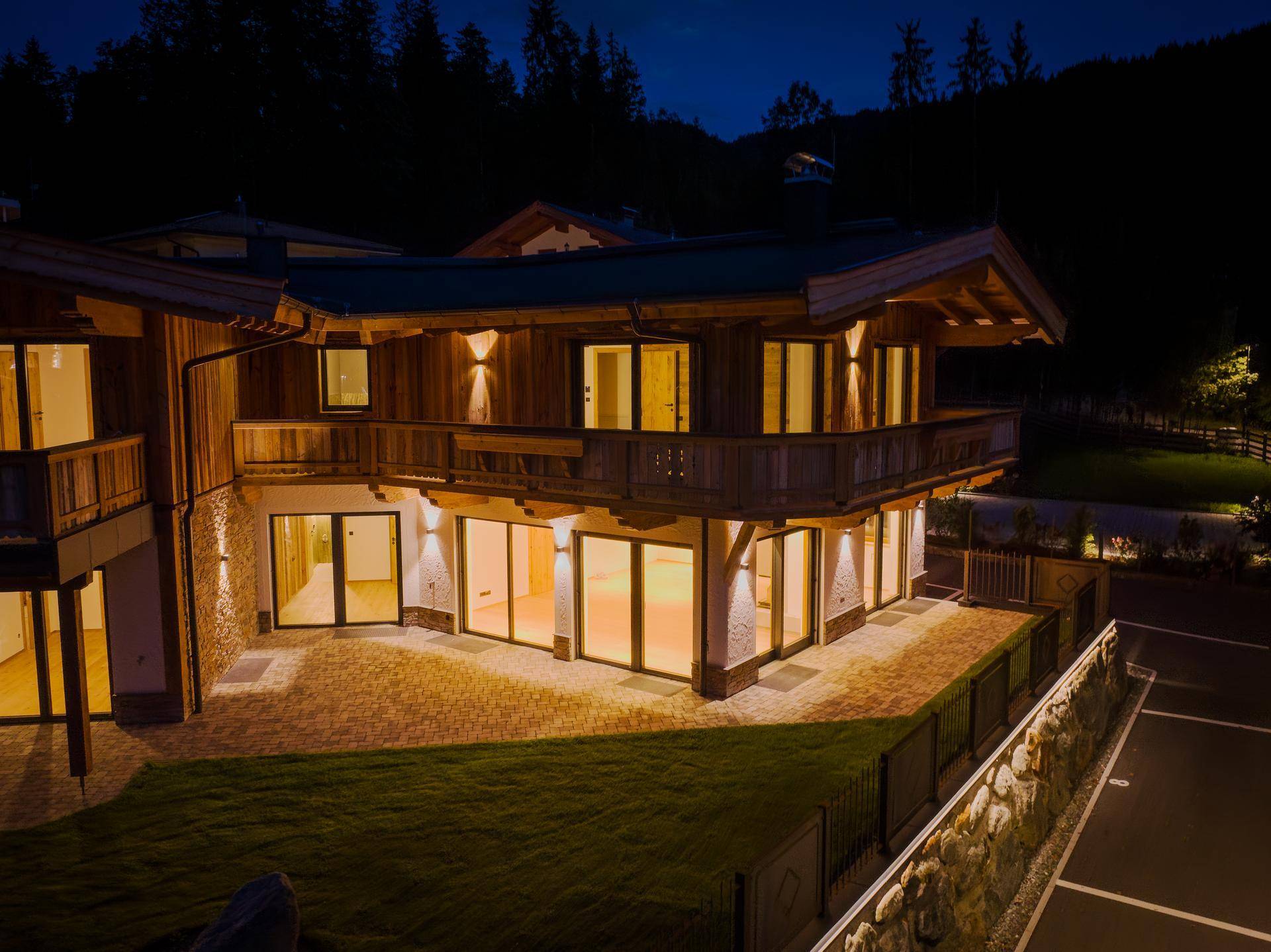 Attraktive Außenansicht des Gebäudes bei Nacht mit beleuchteter Terrasse und Balkonen.
