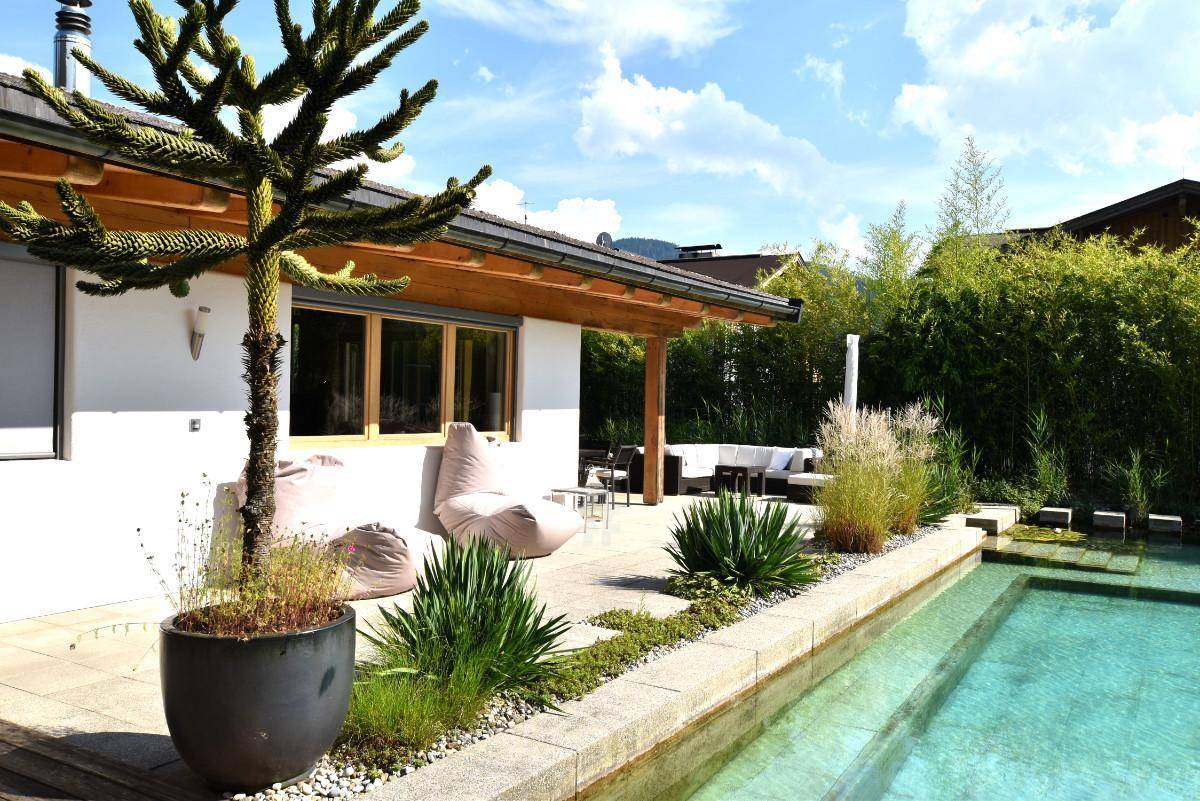 Sonniger Terrassenbereich mit Sitzgelegenheiten und direktem Zugang zum Pool.