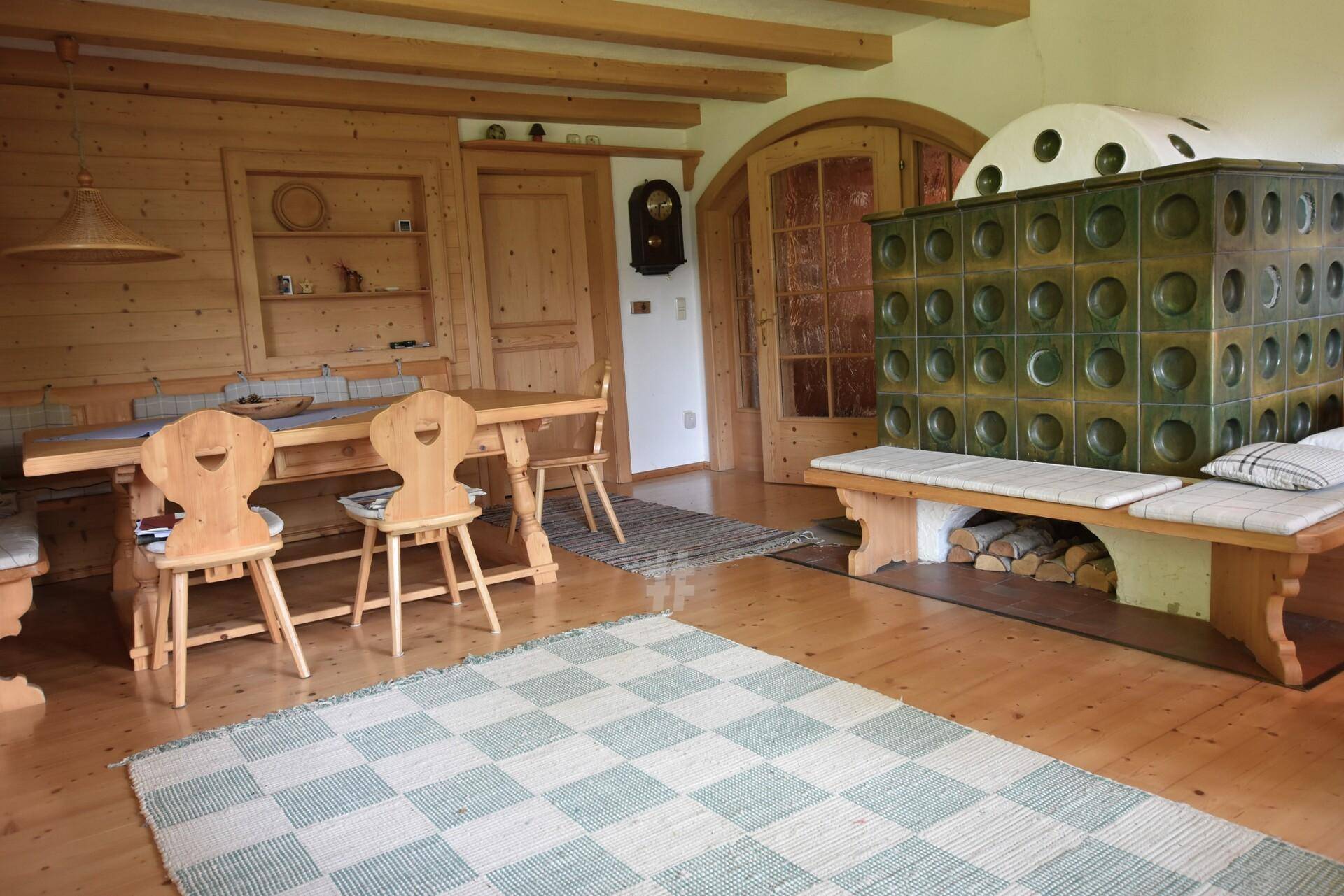Gemütlicher Essbereich mit Holztäfelung, traditionellem Kachelofen und rustikalen Holzmöbeln.