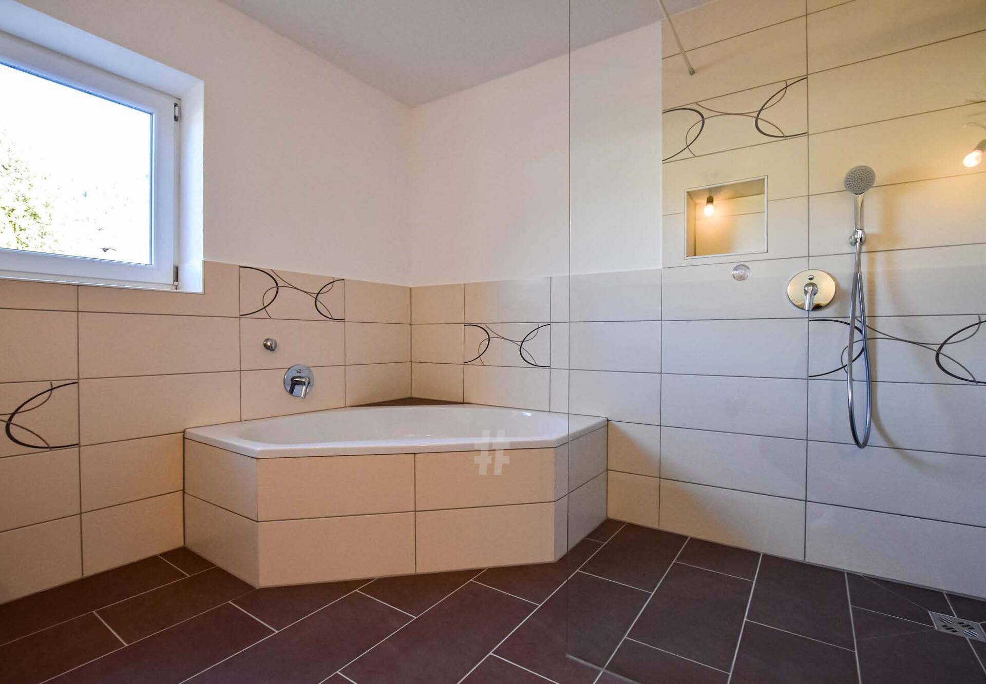 Badezimmer mit Eckbadewanne, Dusche, Fliesen und einem Fenster für Tageslicht.