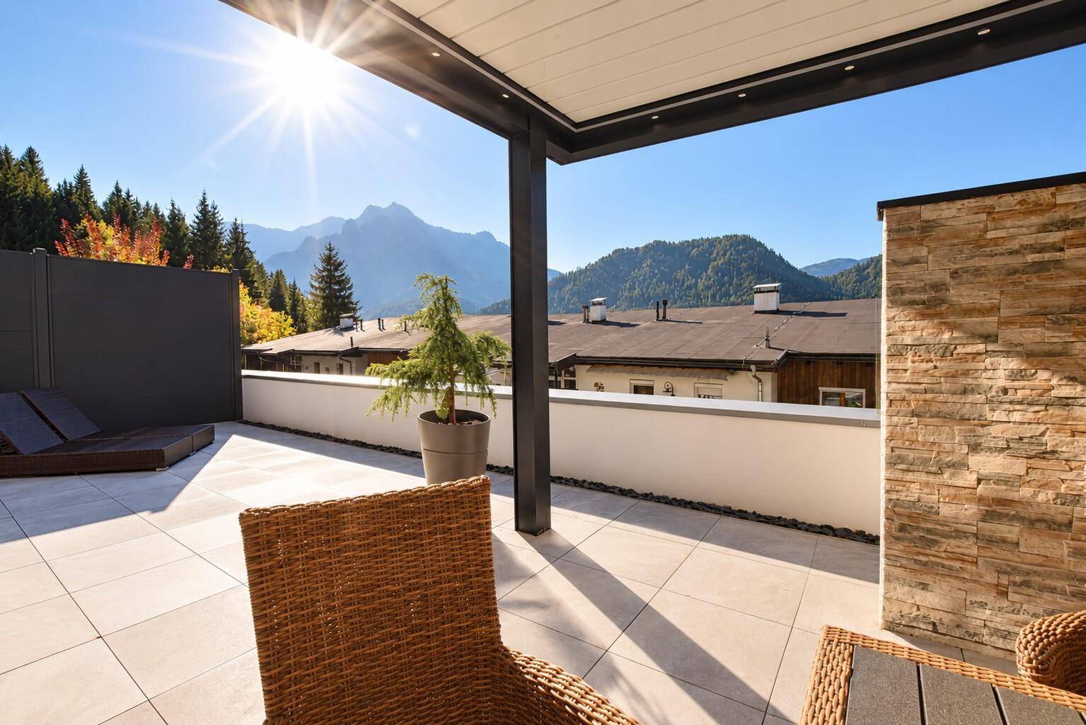 Sonnenterrasse mit Fliesenboden, Korbstuhl und atemberaubendem Bergblick in die Ferne.
