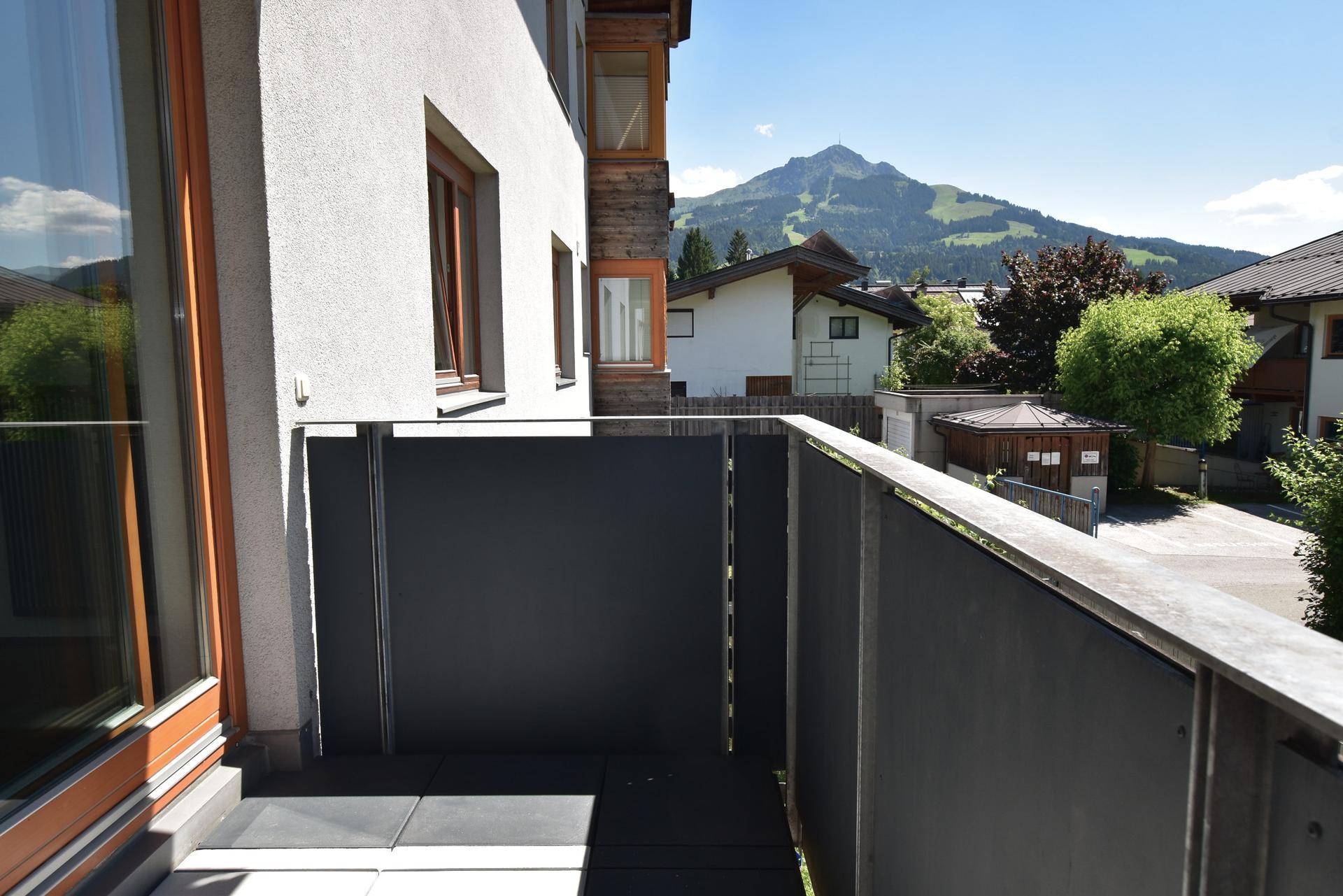 Balkon mit moderner Brüstung und Blick auf die umliegende Bebauung und einen Berg.