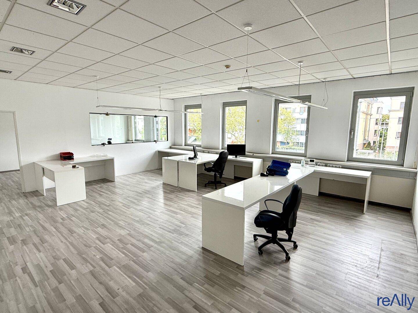 Heller Büroraum mit modernen Schreibtischen und ergonomischen Stühlen, ideal für Teamarbeit.