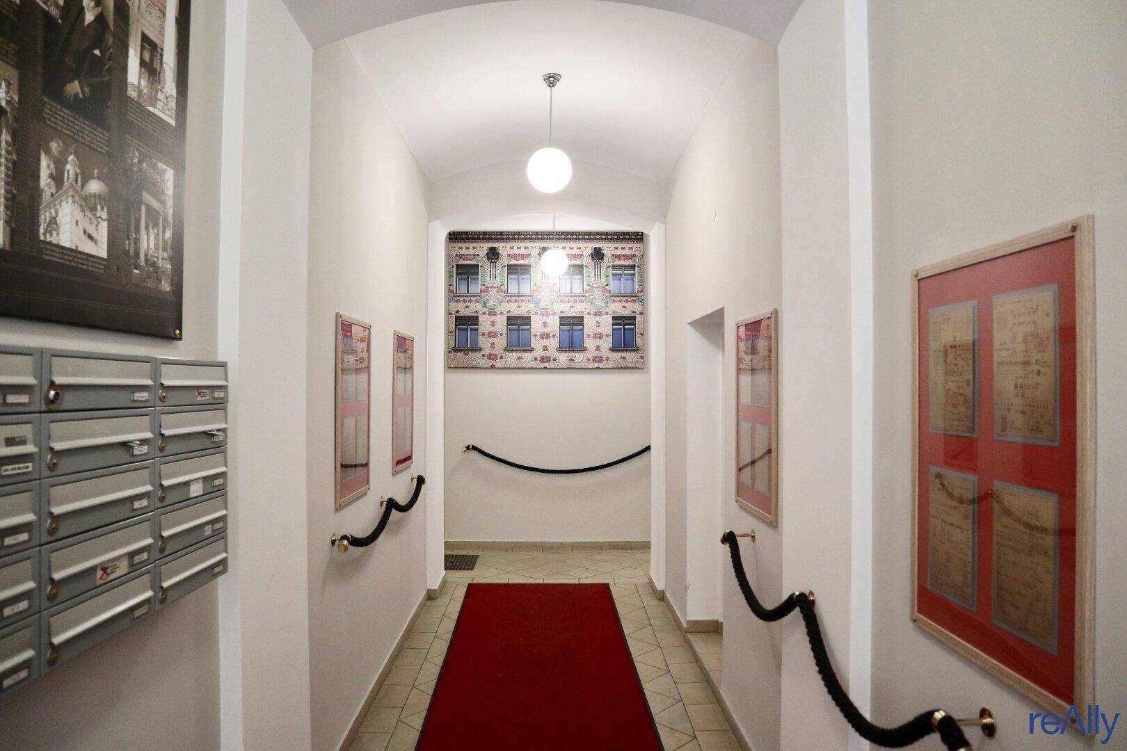Langer Flur mit gewölbter Decke, rotem Teppich und dekorativen Elementen an den Wänden.
