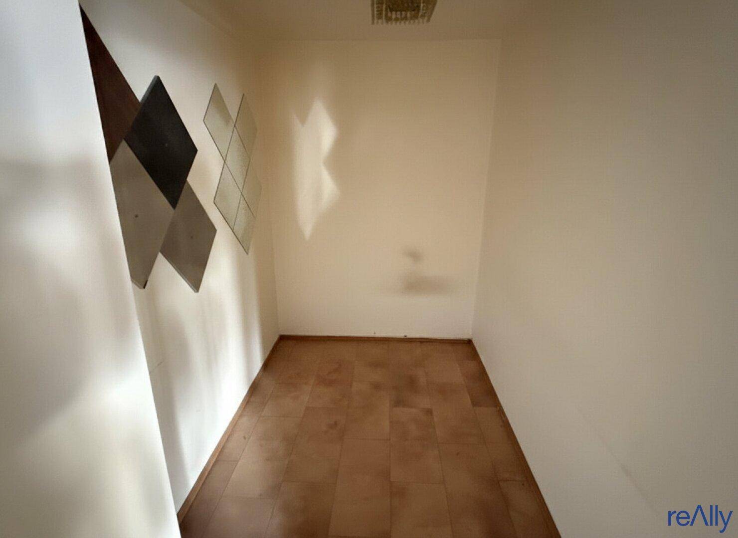 Kleiner, leerer Raum mit Fliesenboden und weißen Wänden, möglicherweise ein Abstellraum oder Lager.